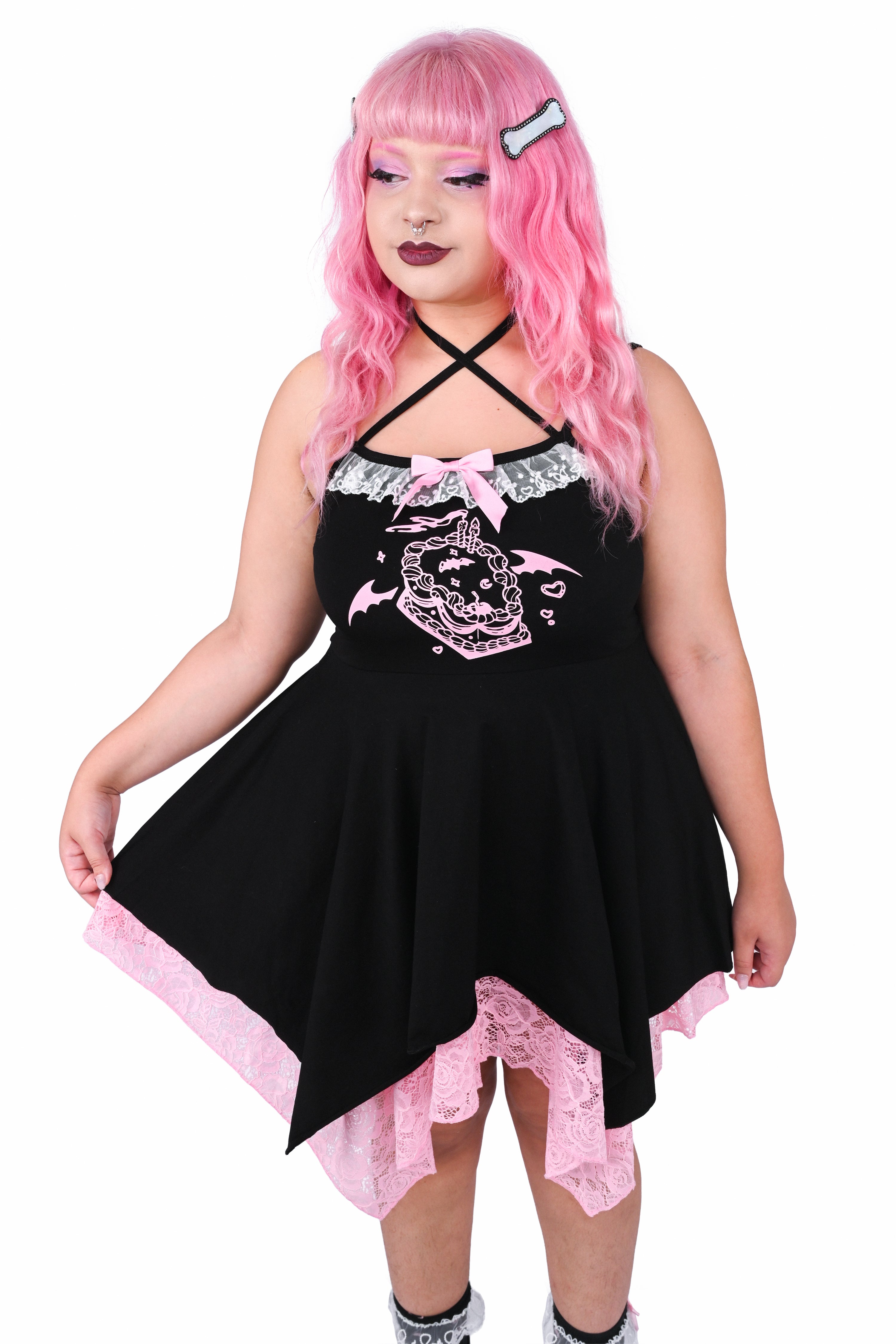 Model wearing a black dress with a cake graphic and pink and white lace details