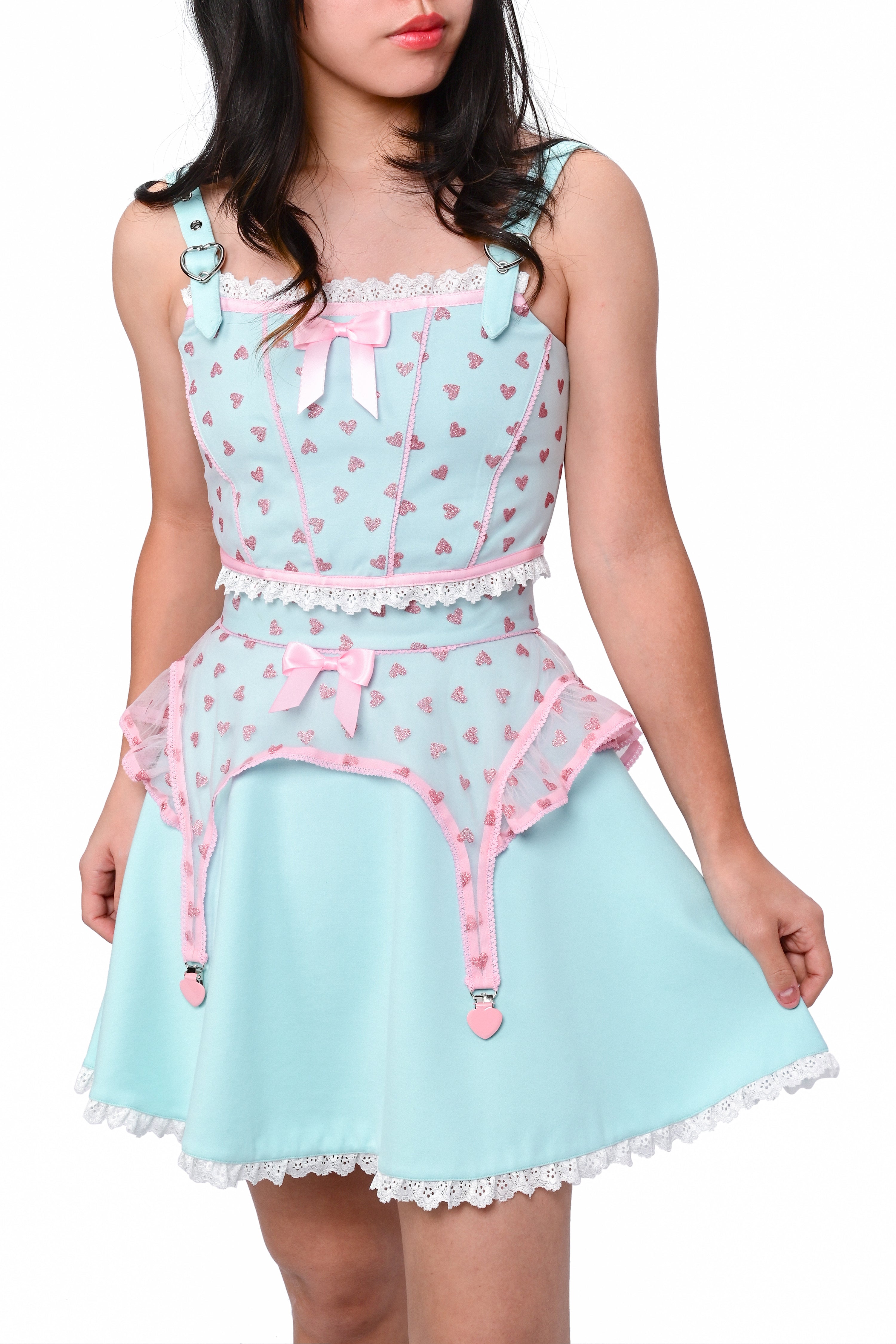 A person wearing a mint green skater skirt with a lace hem and pink details, paired with a matching top featuring a heart pattern.