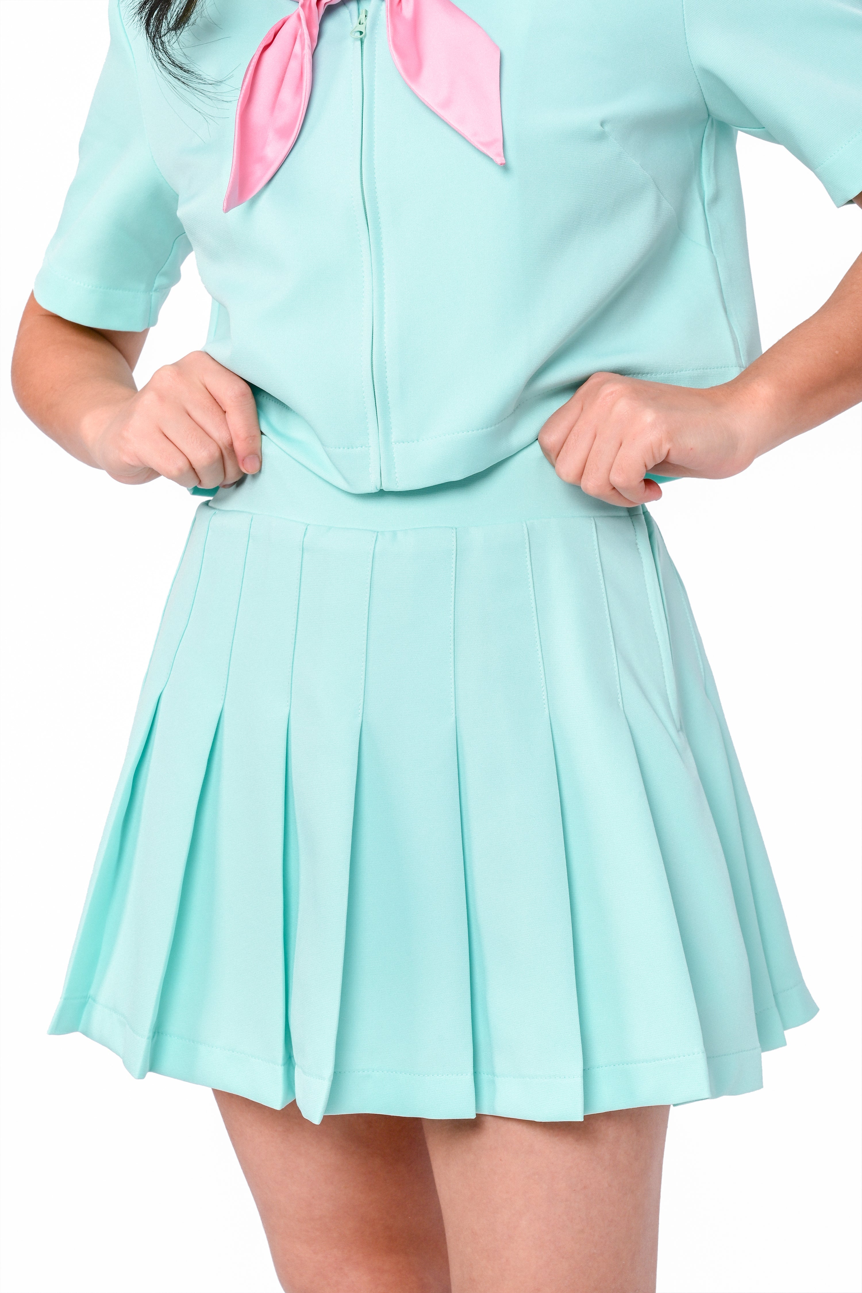A model wearing a mint pleated skirt with built-in shorts and a matching top