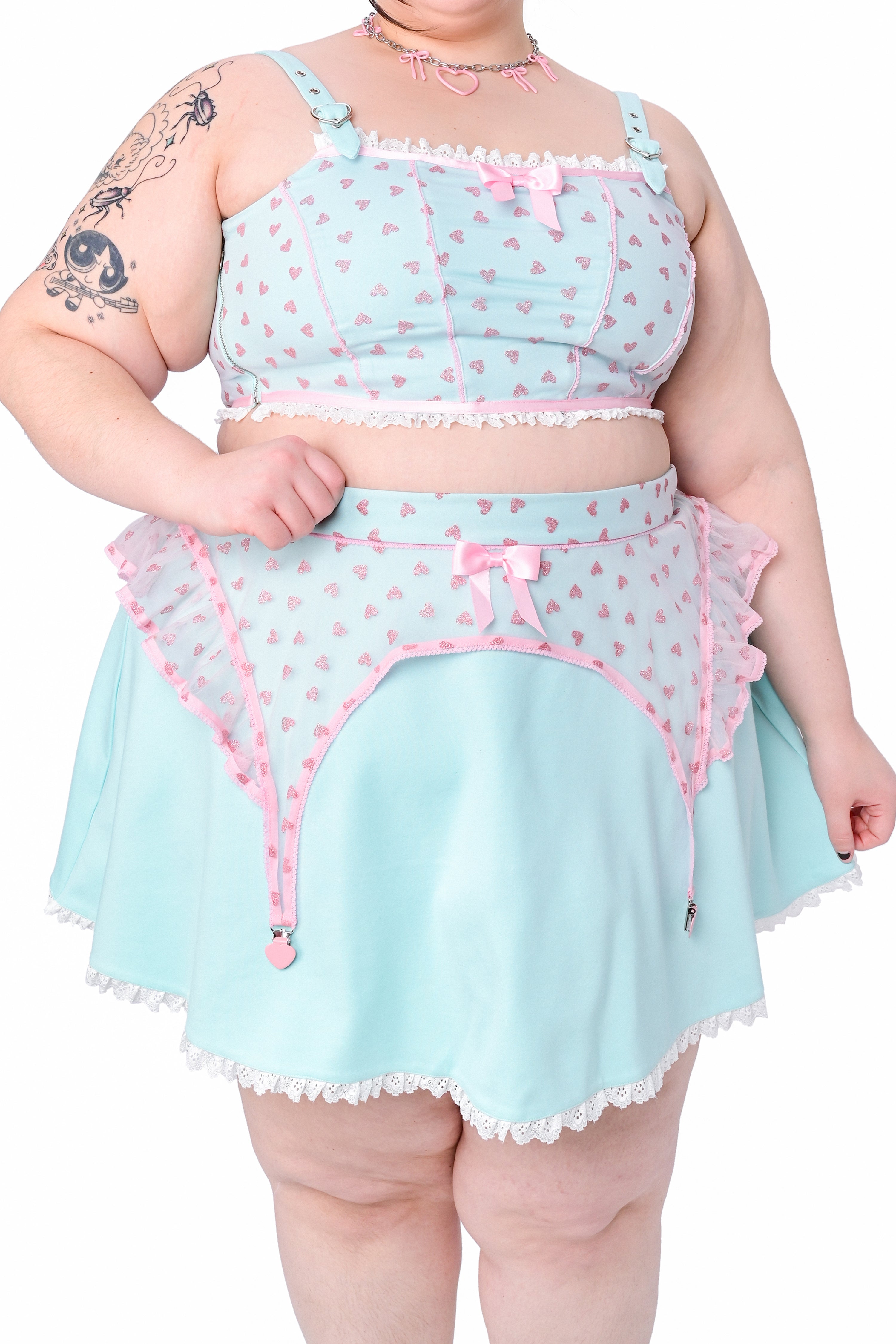 A person wearing a mint green skater skirt with a lace hem and pink details, paired with a matching top featuring a heart pattern.