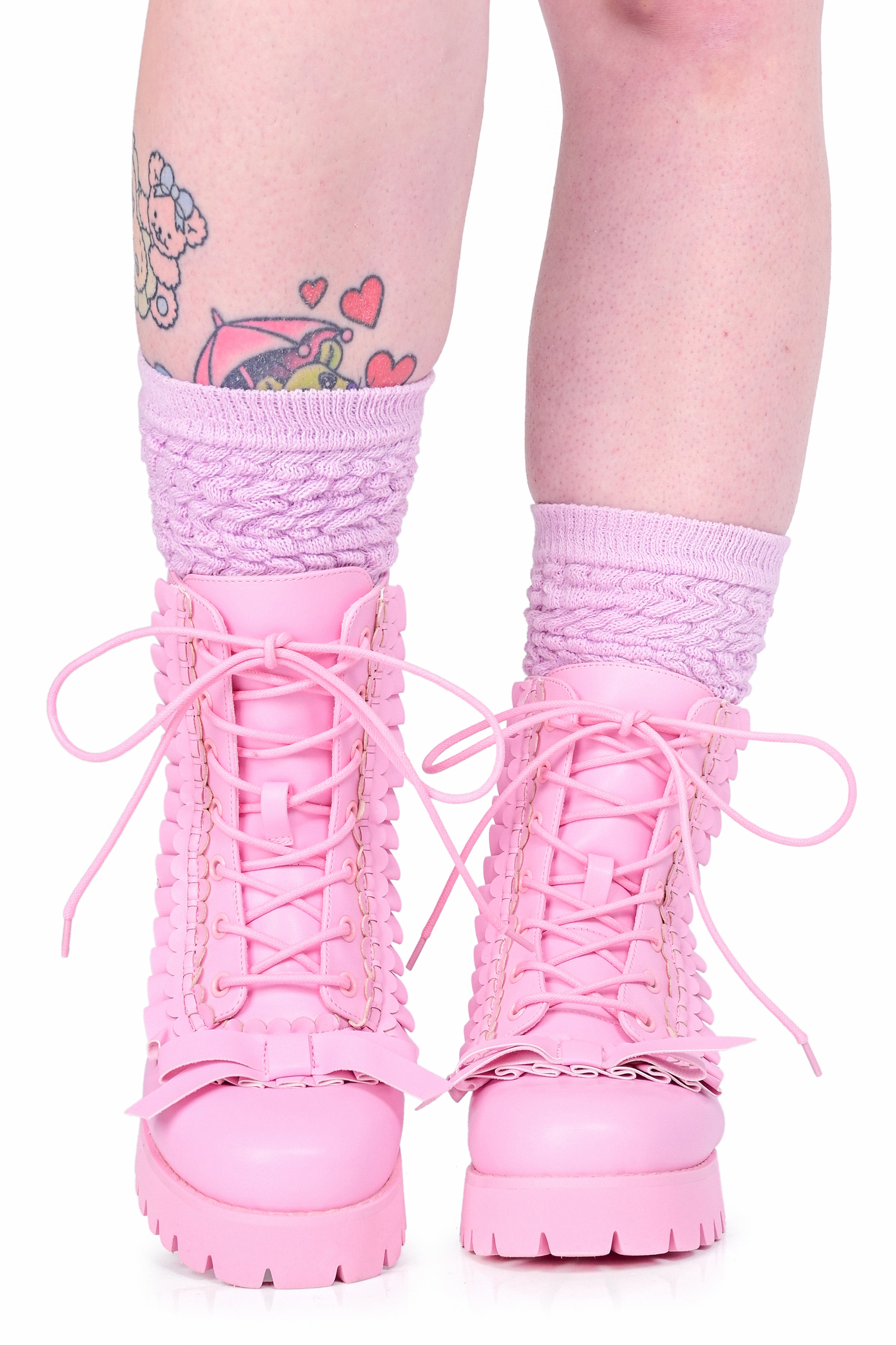 A model wearing a pair of lace up pink boots with ruffle details and a bow