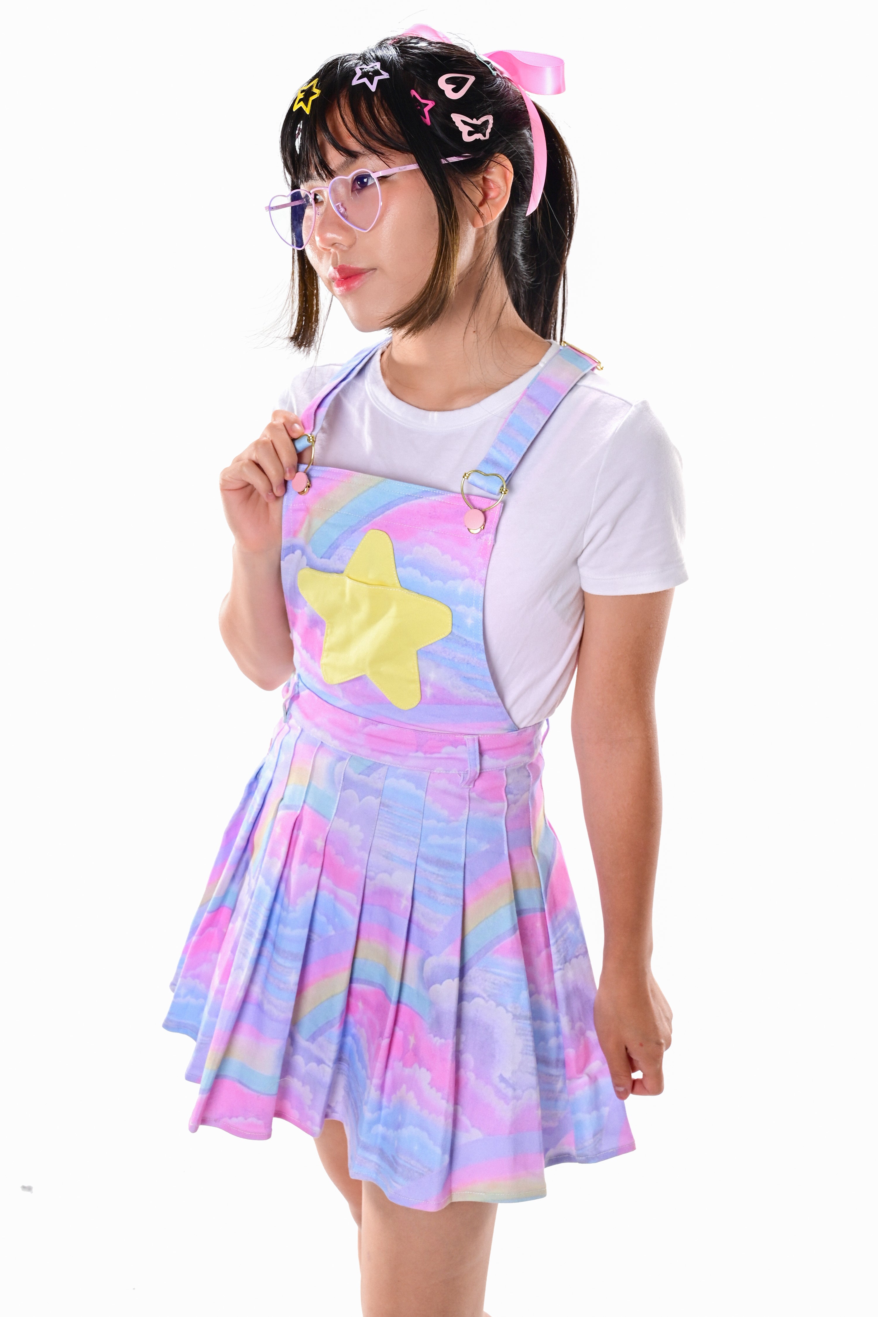 A model wearing a multicolored pinafore dress with a star applique, paired with a white long-sleeved top