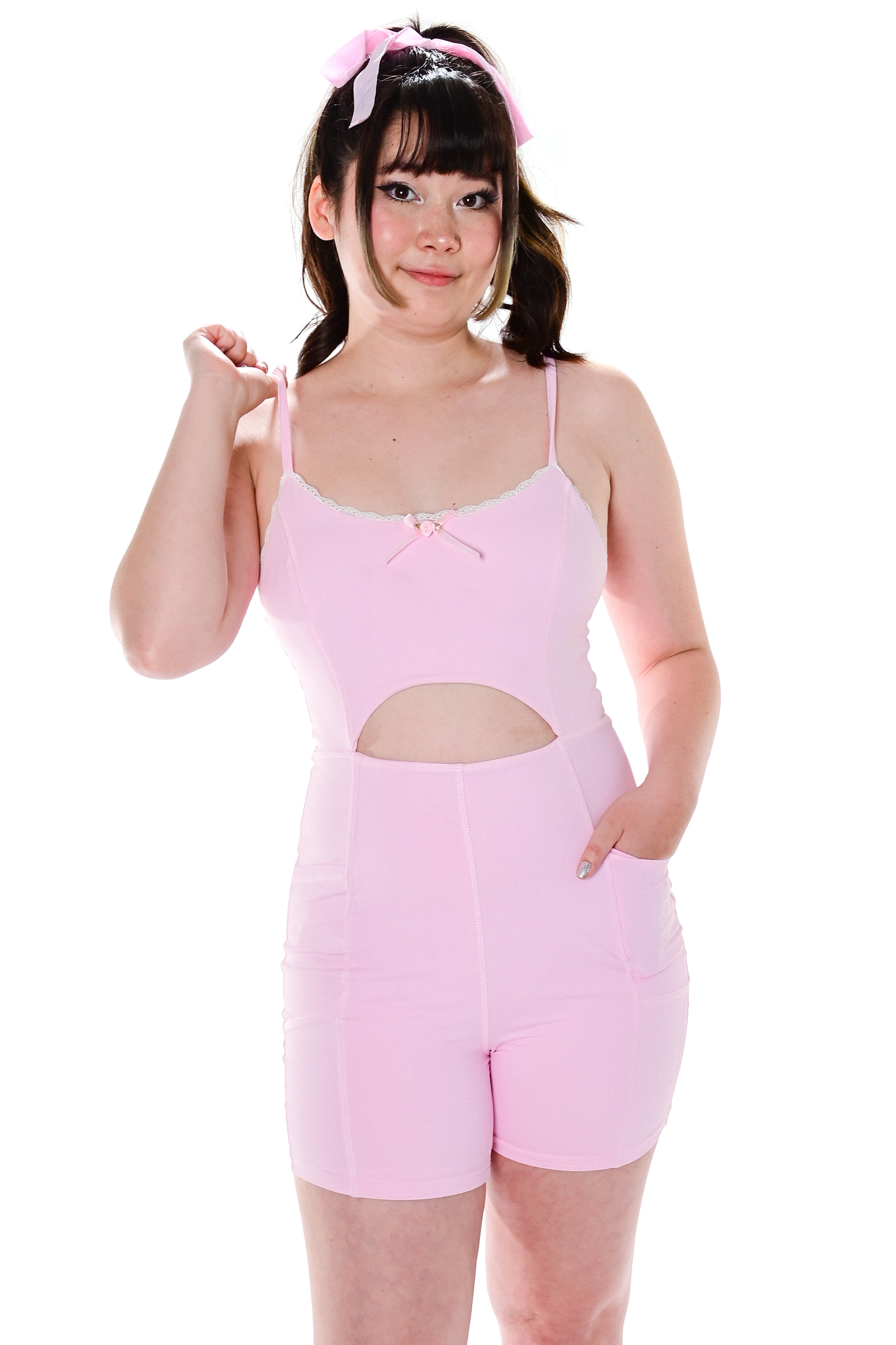 A model wearing a pink sleeveless bodysuit with adjustable straps and a cutout detail at the waist