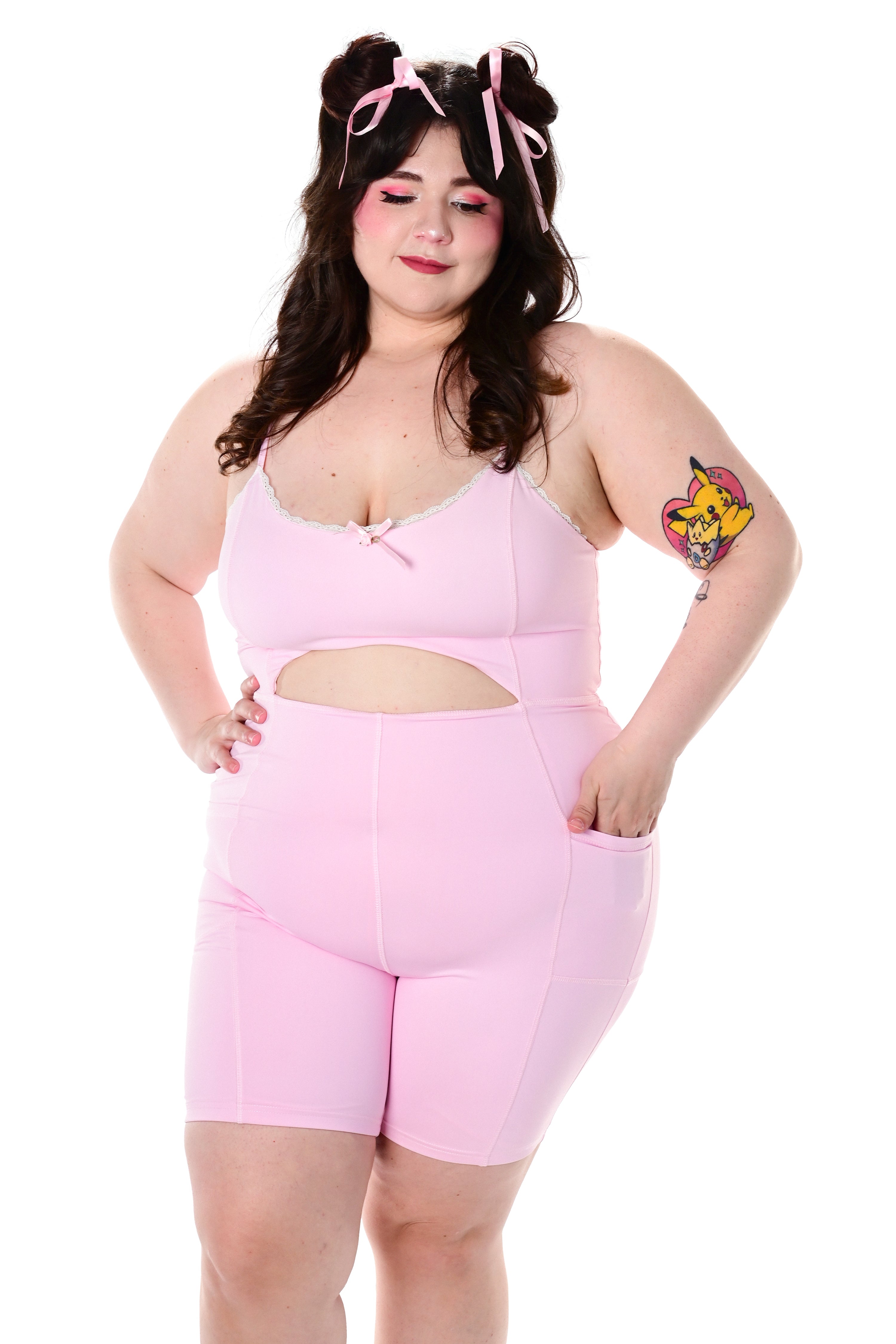 A model wearing a pink sleeveless bodysuit with adjustable straps and a cutout detail at the waist
