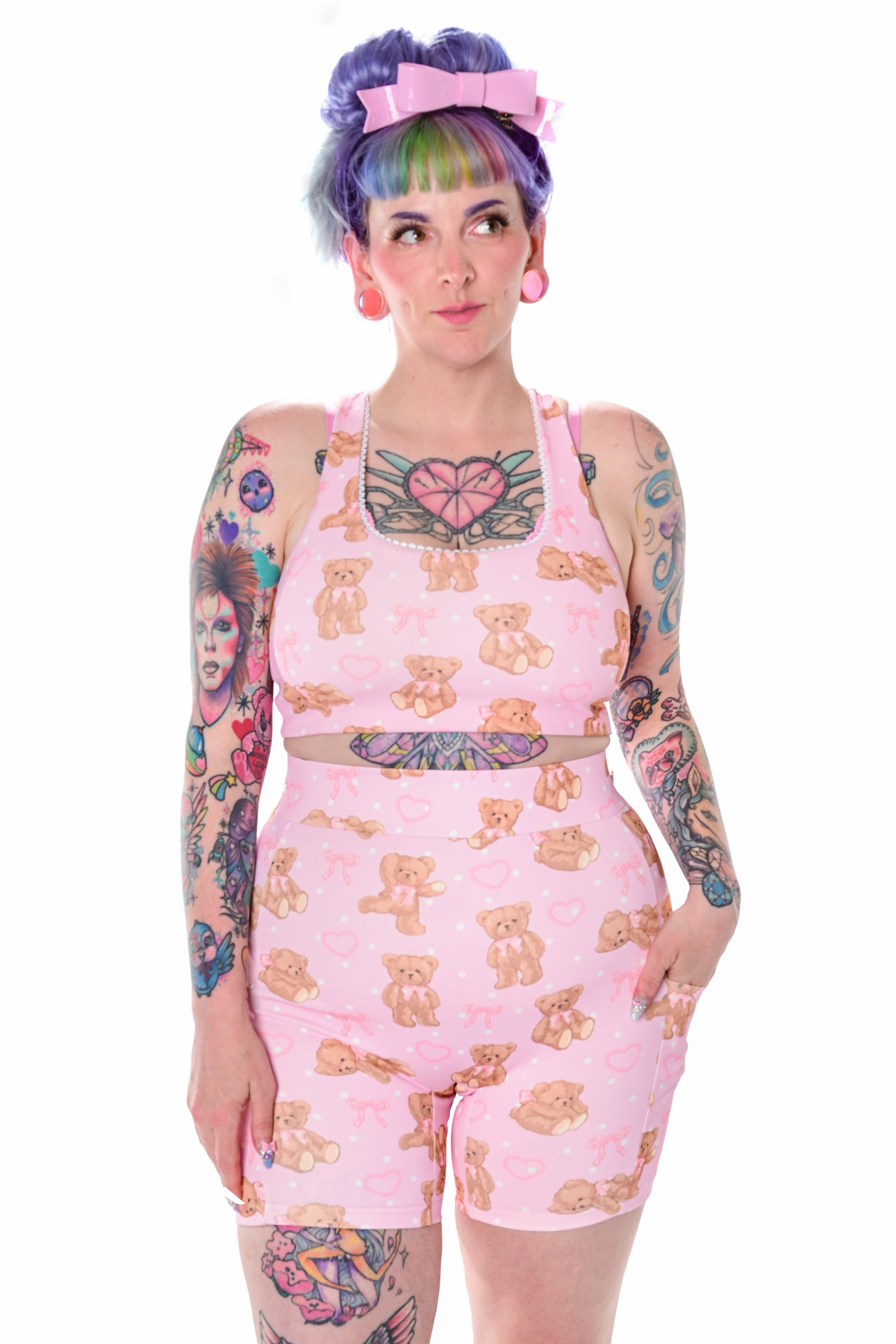 A model wearing a pink teddy bear print sports bra with delicate scallop lace trim, with a pair of matching biker shorts