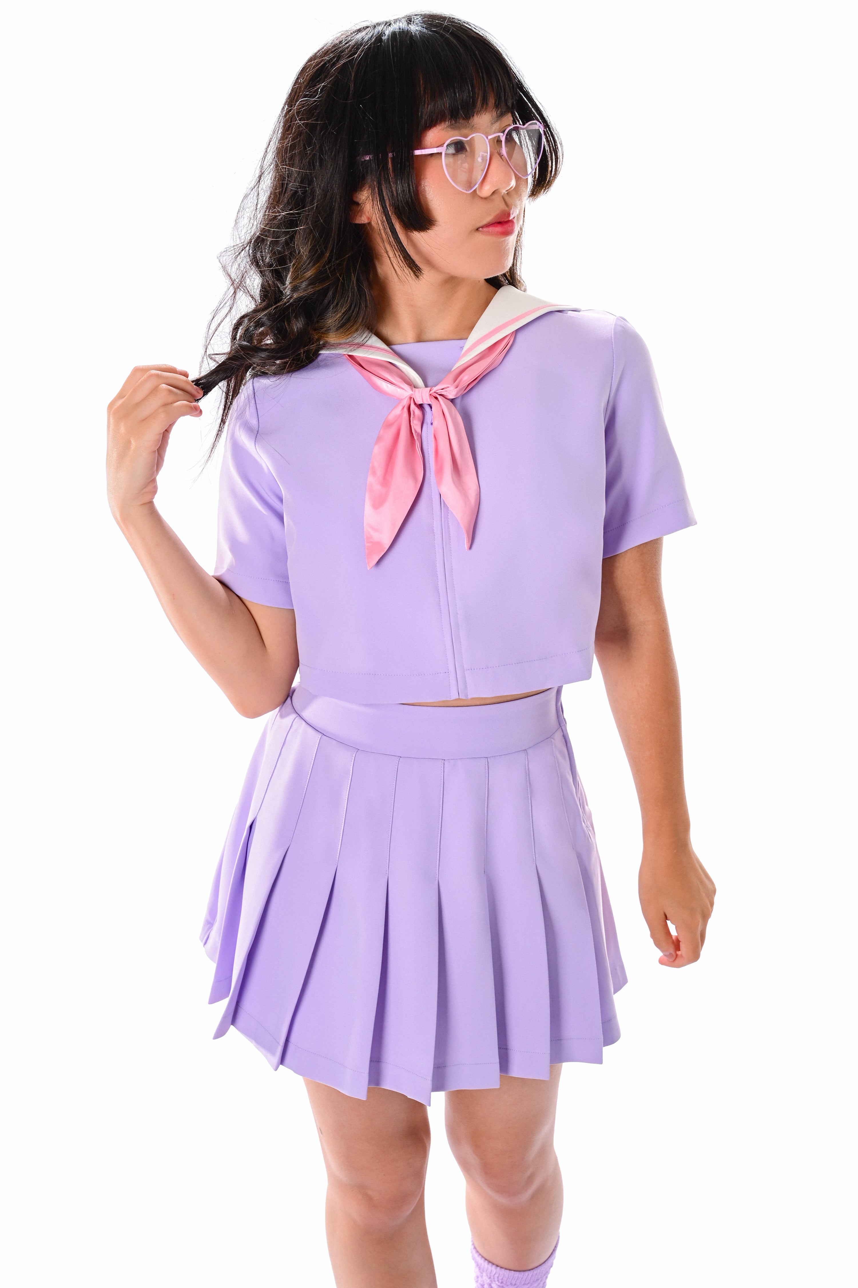 A person wearing a lavender colored sailor-style top with a white collar and a pink neck tie, paired with a pleated skirt.