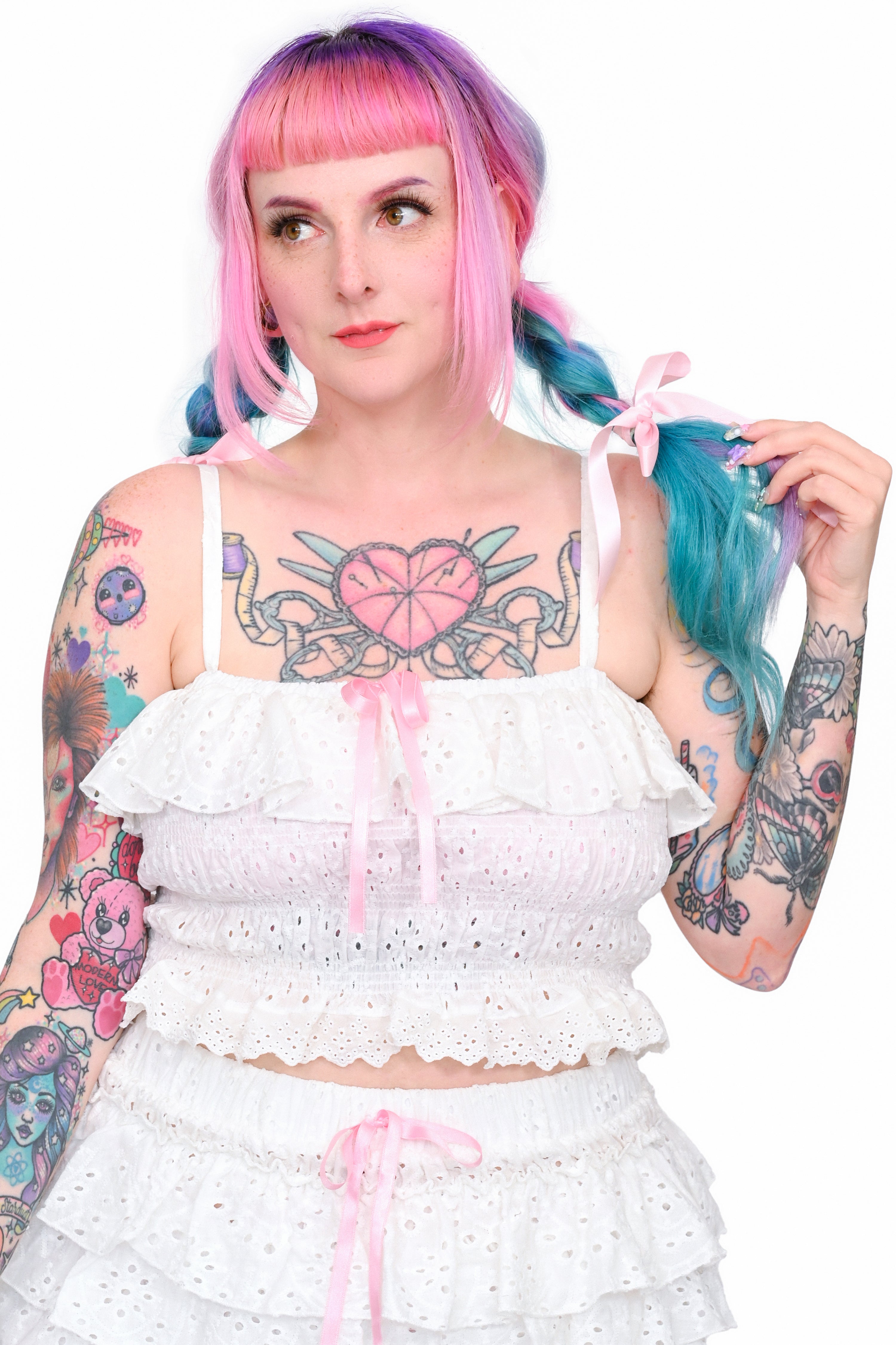 A person wearing a white eyelet lace ruffle cami with pink satin bows and matching shorts.