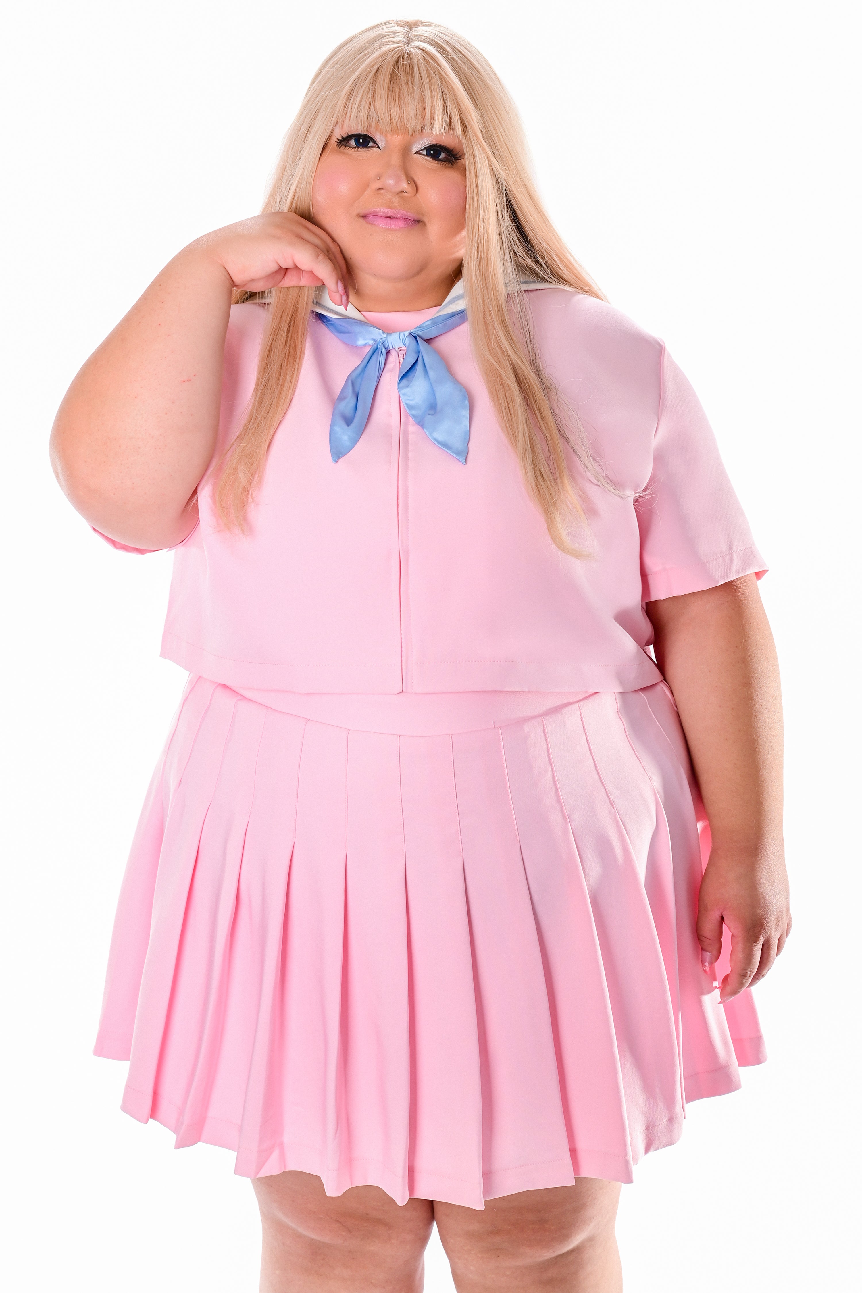 A person wearing a pink sailor-style top with a blue neck tie and a matching pleated skirt