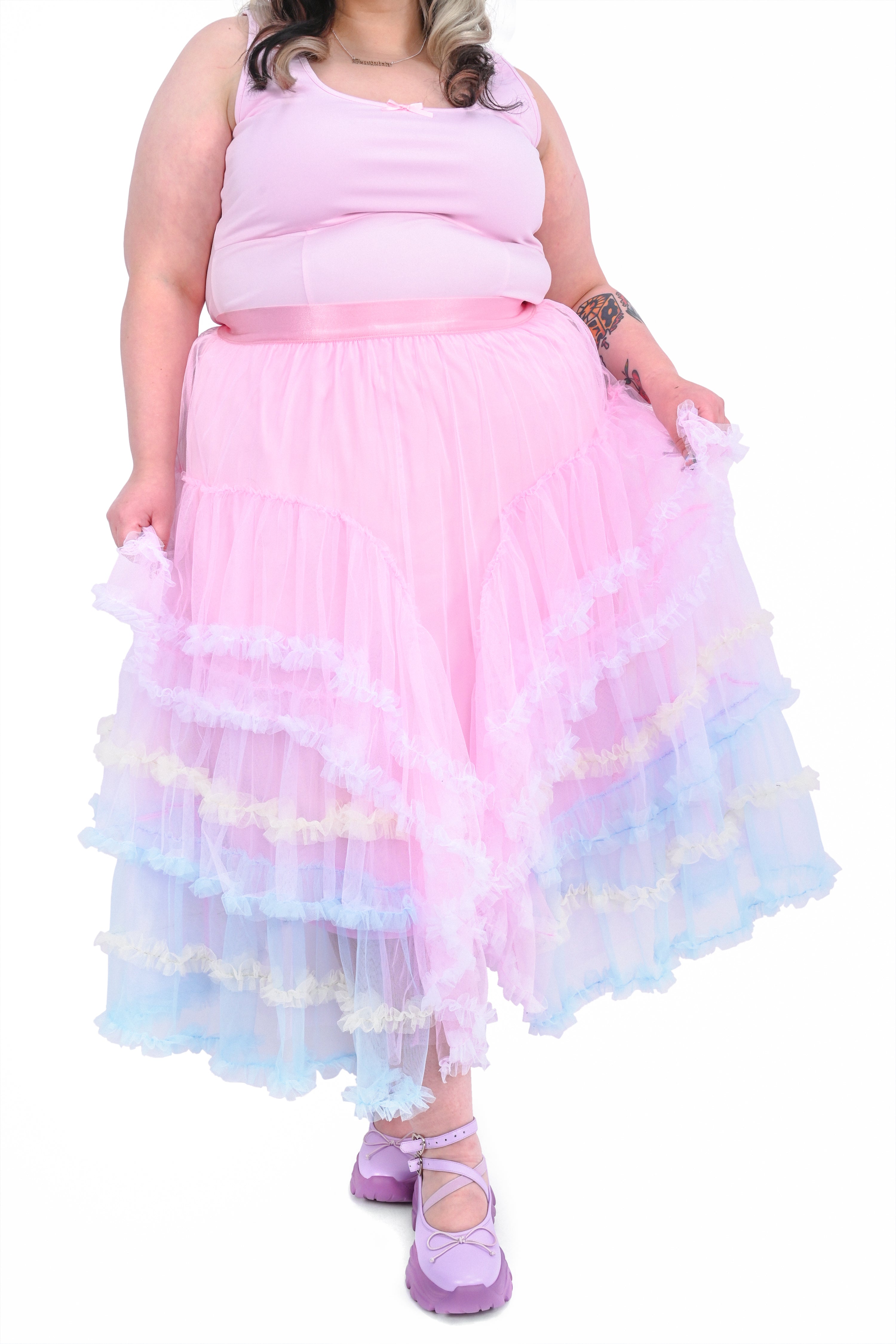 A person wearing a ruffled tiered maxi skirt with multicolored layers of pastel tulle