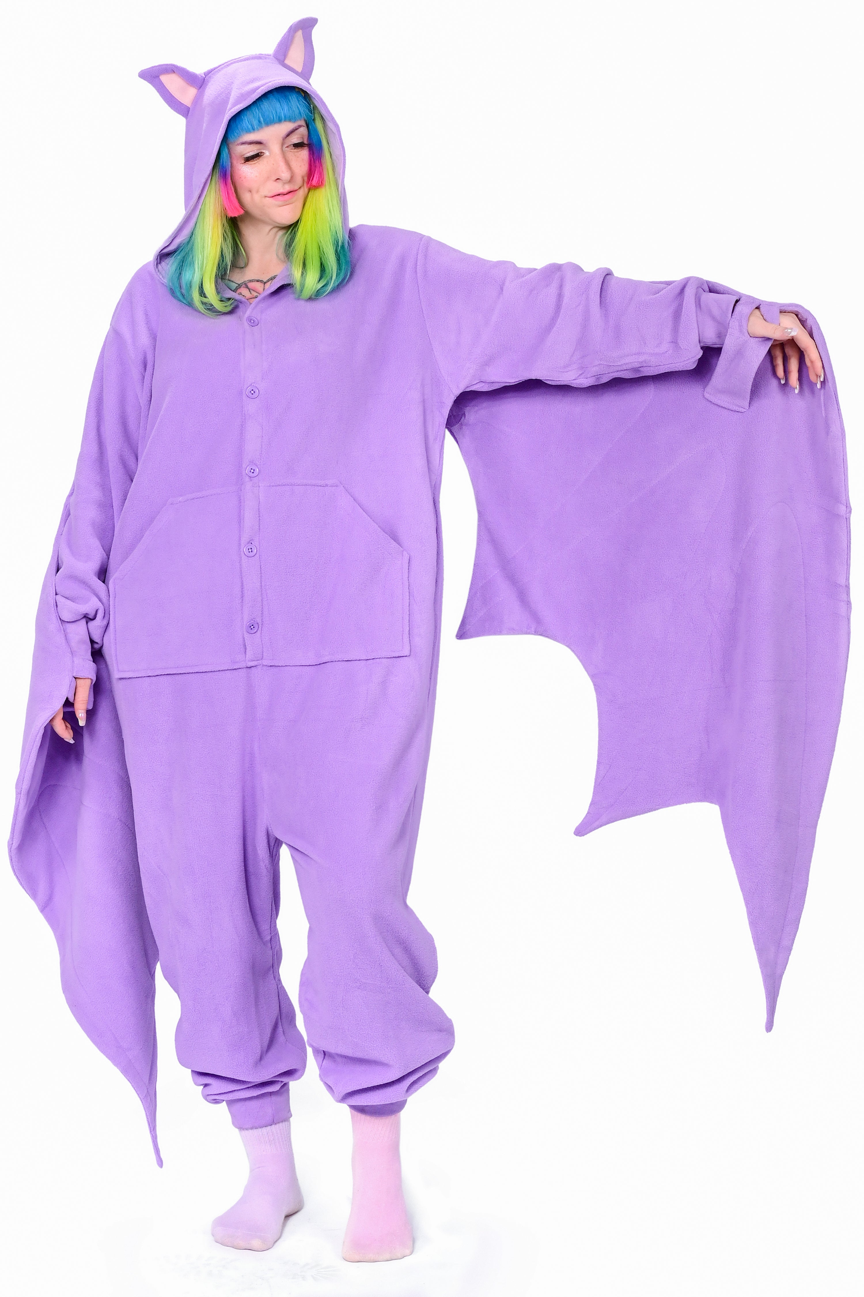 A person wearing a purple fruit bat onesie with a hood featuring bat ears, with a wing extended