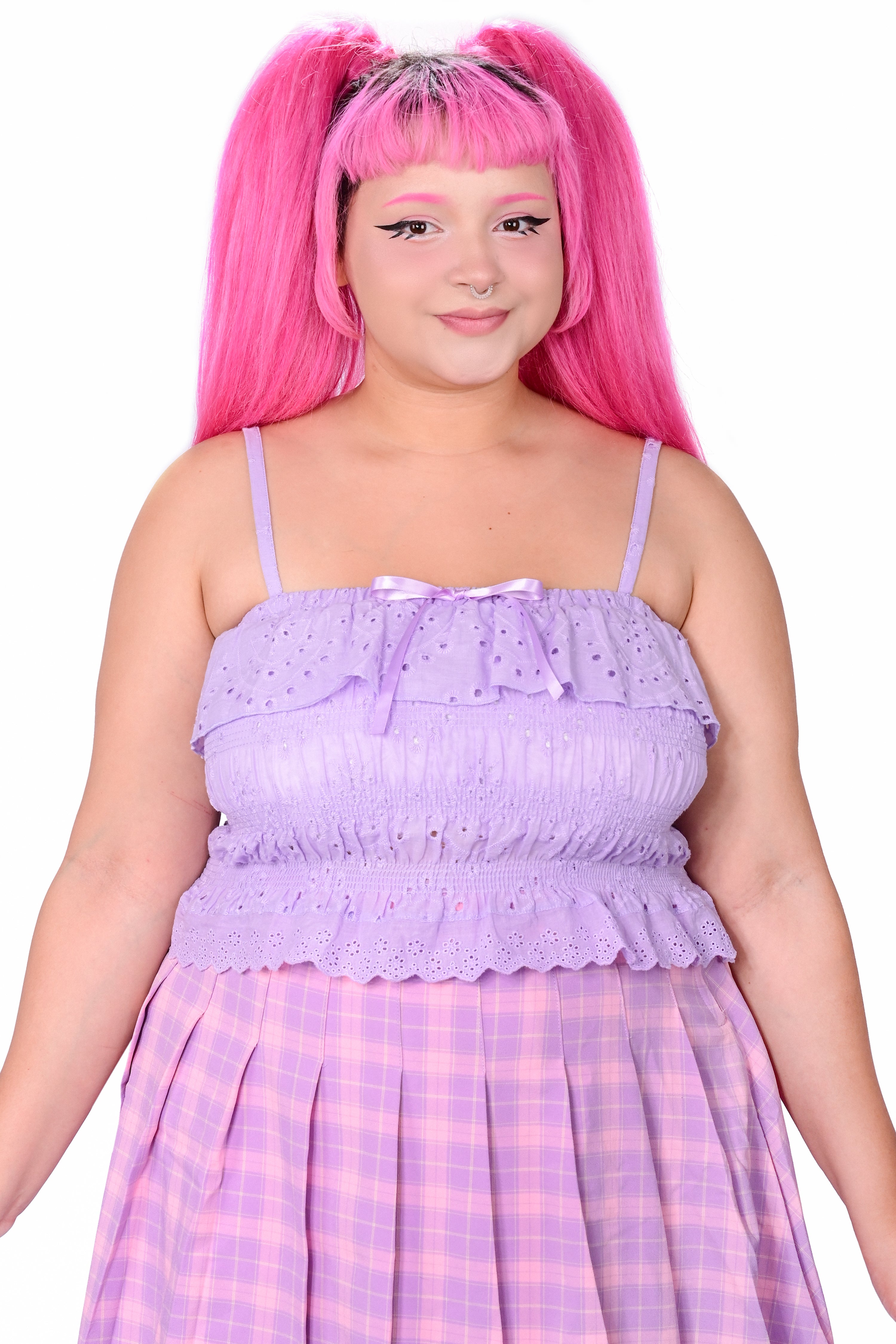 A person wearing a purple, ruffled, eyelet lace camisole top with adjustable straps and satin bows, paired with matching shorts.