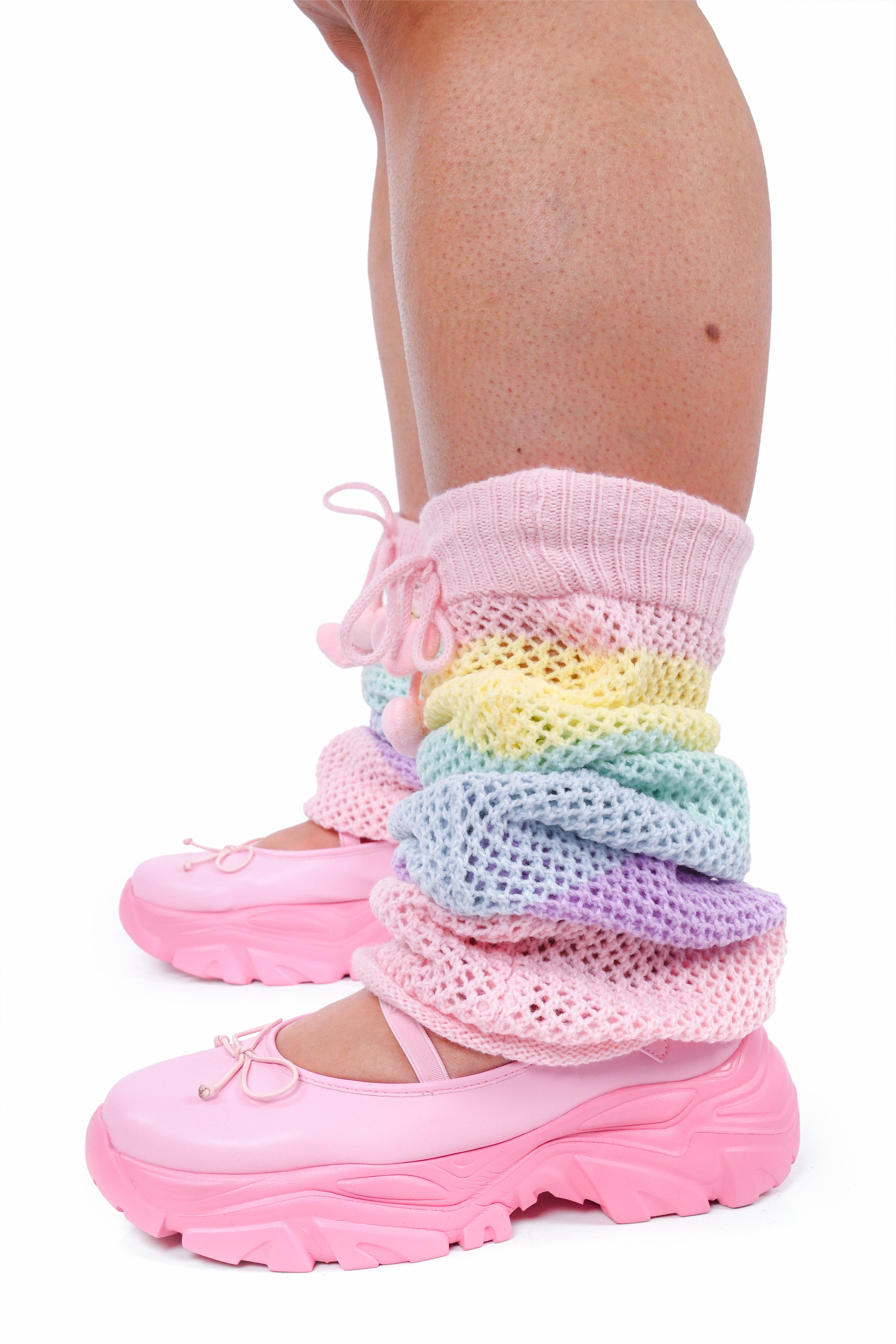 Pastel knitted leg warmers over pink shoes on a white background