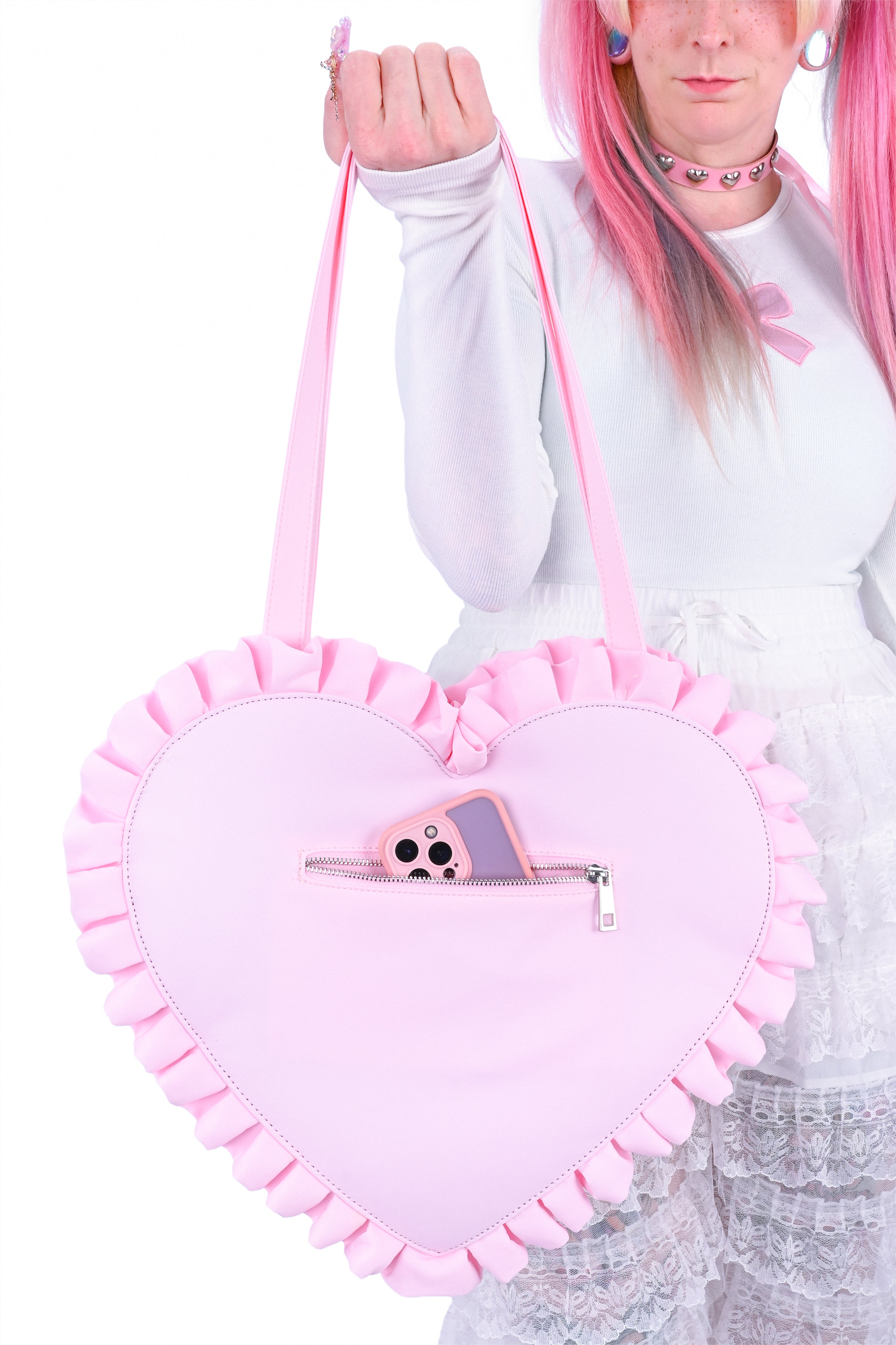 Person holding a pink heart-shaped bag with ruffles