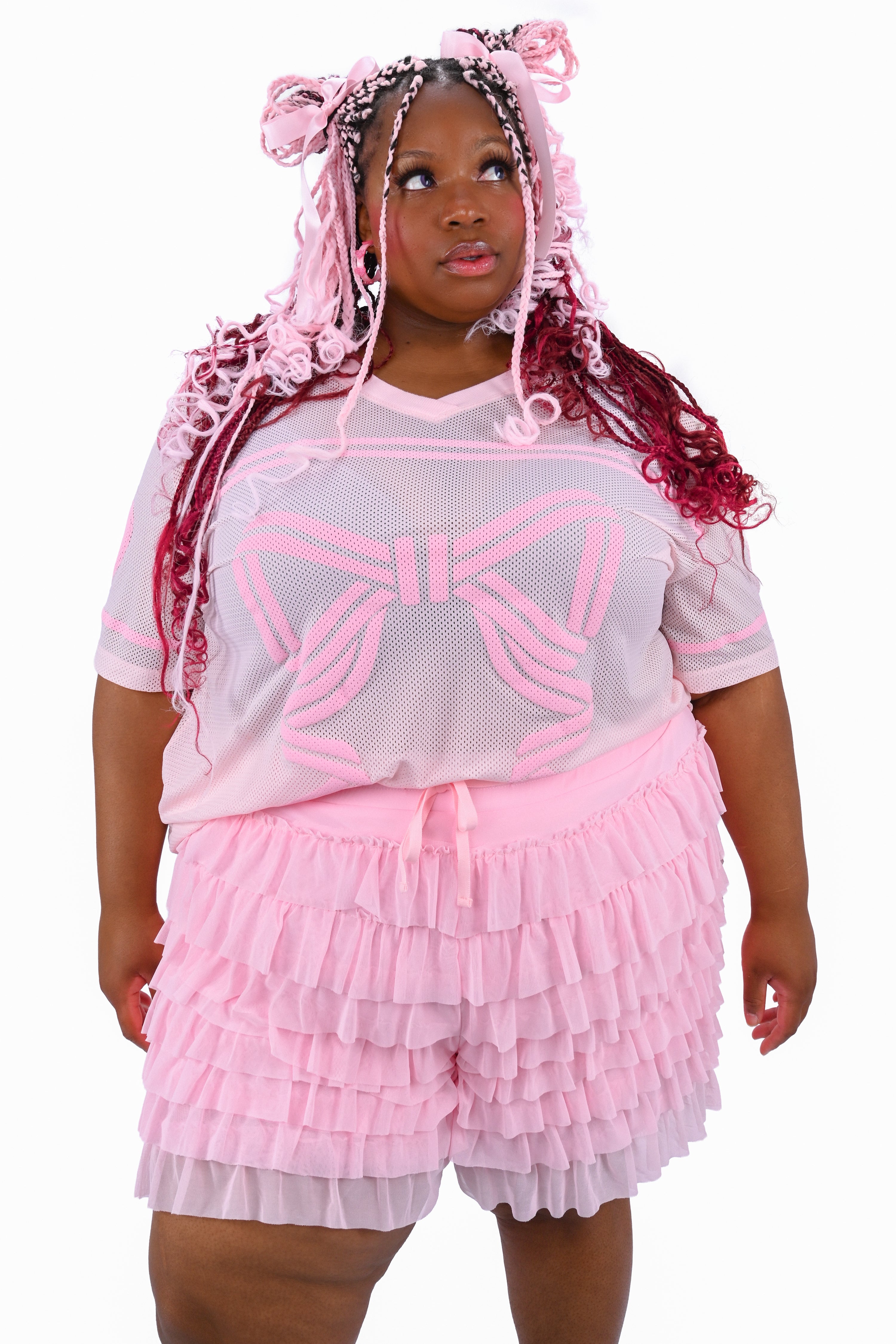 A person wearing pink ruffled mesh shorts and a matching pink jersey