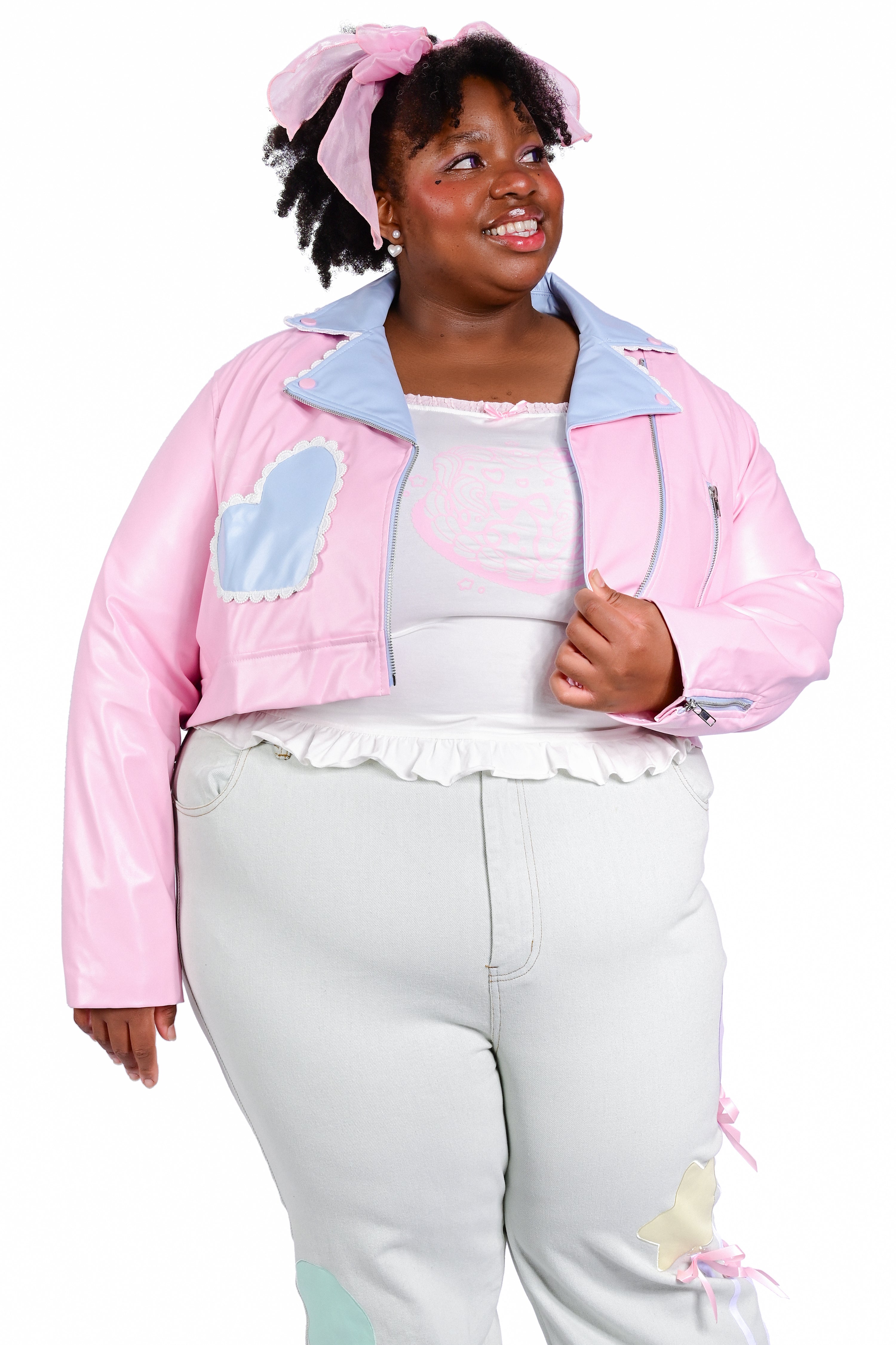 A person wearing a pink cropped moto jacket with blue accent pockets and white trimmed lace