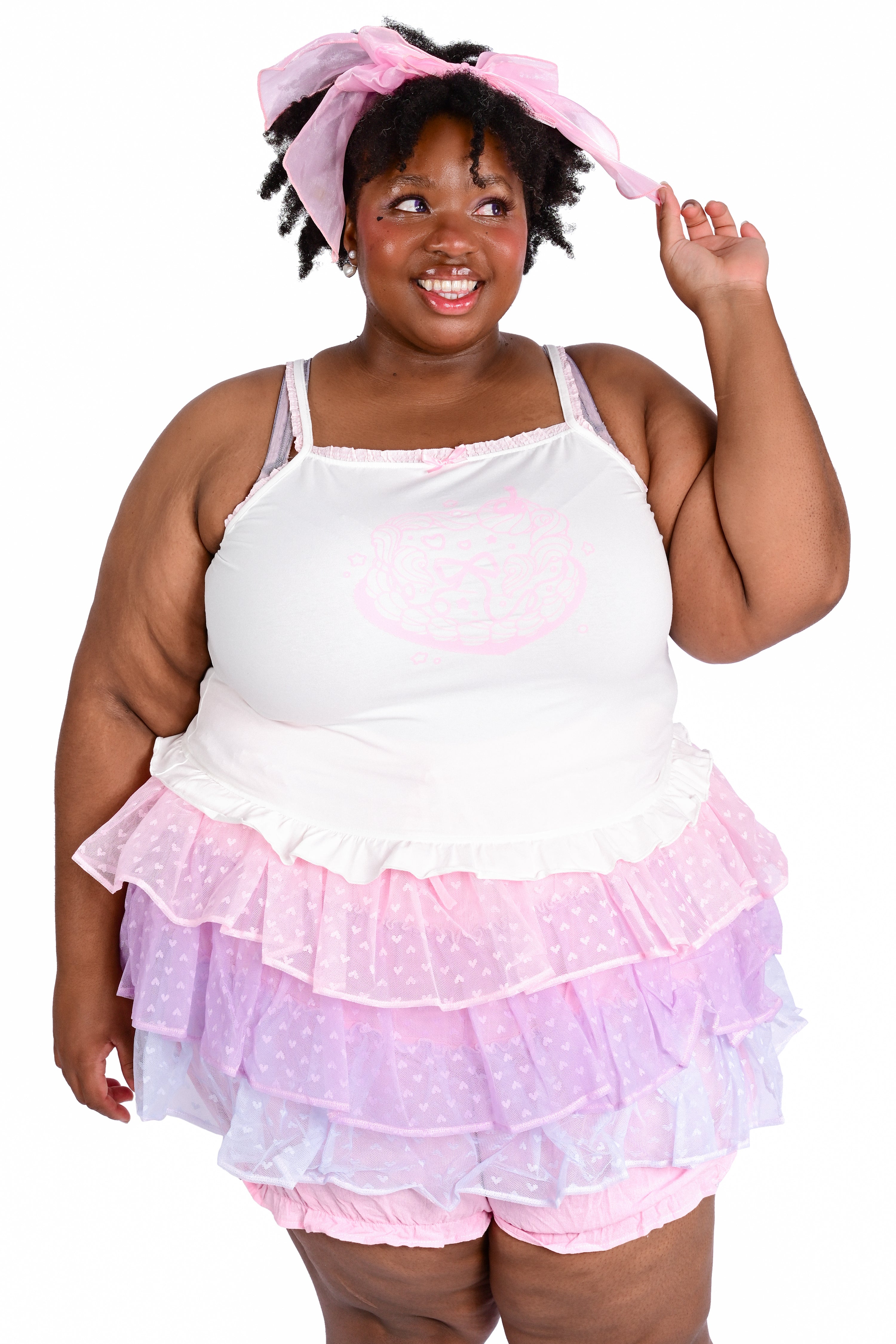 A person wearing a white cami with a cake graphic, paired with a ruffled skort