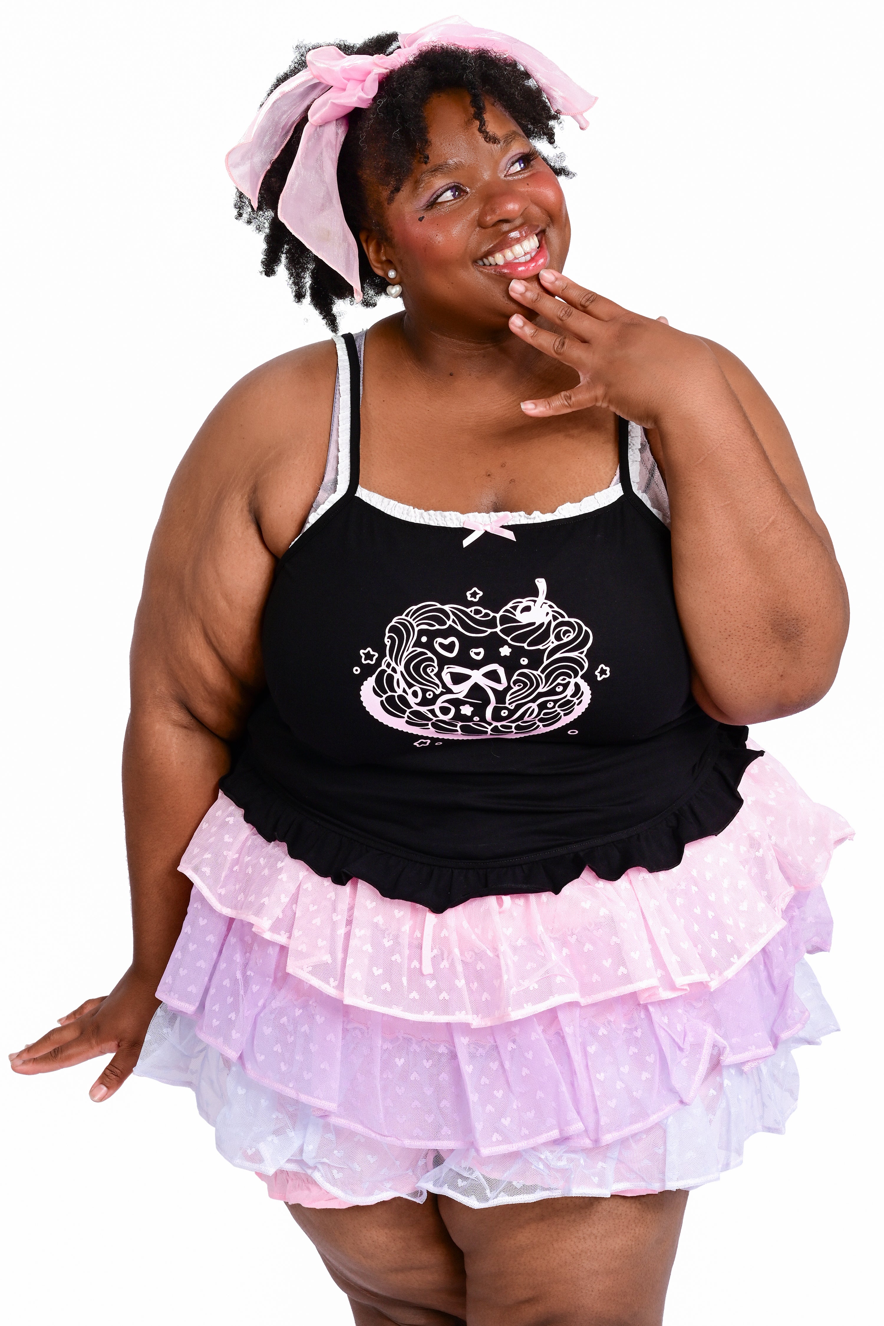 A person wearing a black cami with a cake graphic, paired with a ruffled skort