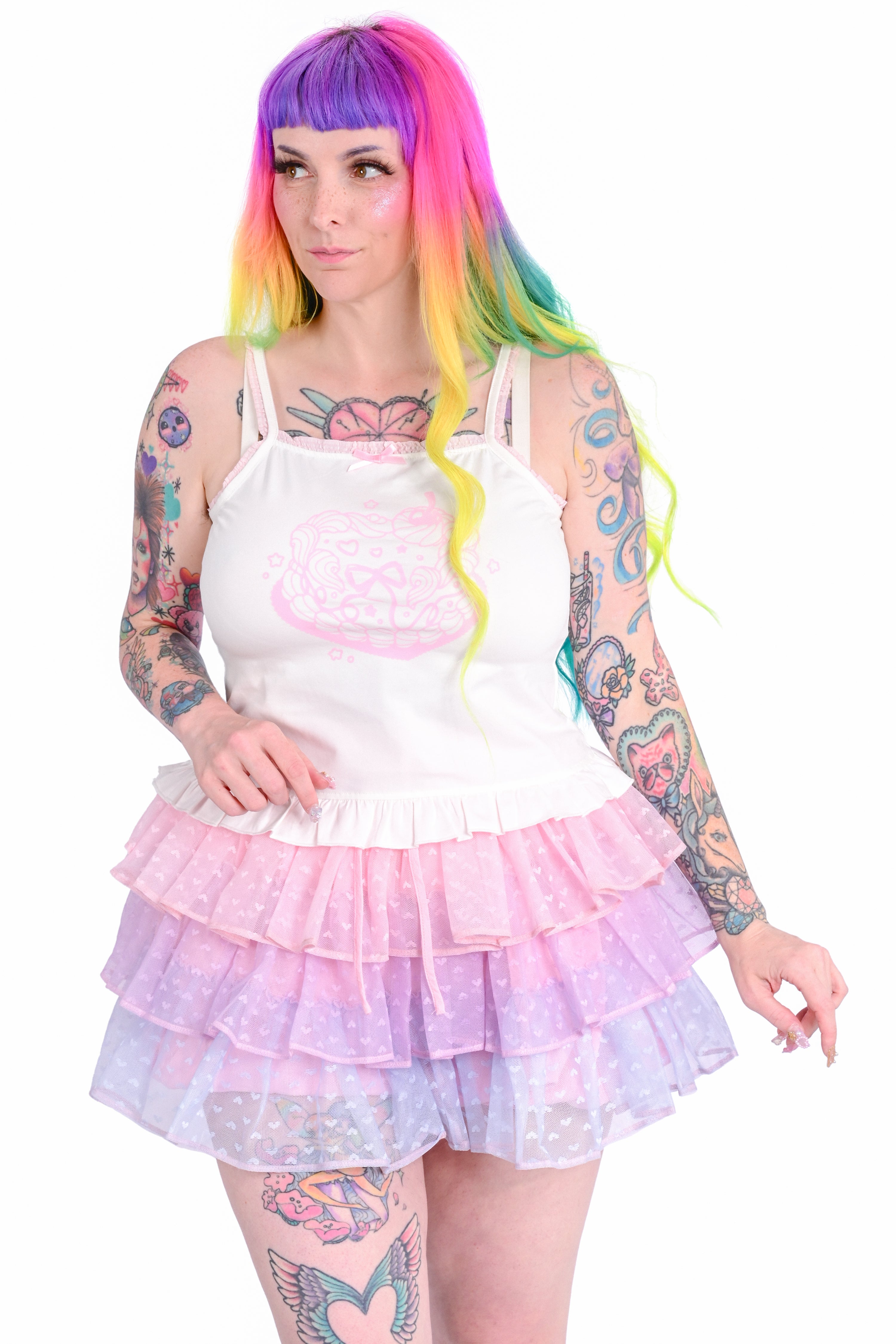 A person wearing a white cami with a cake graphic, paired with a ruffled skort