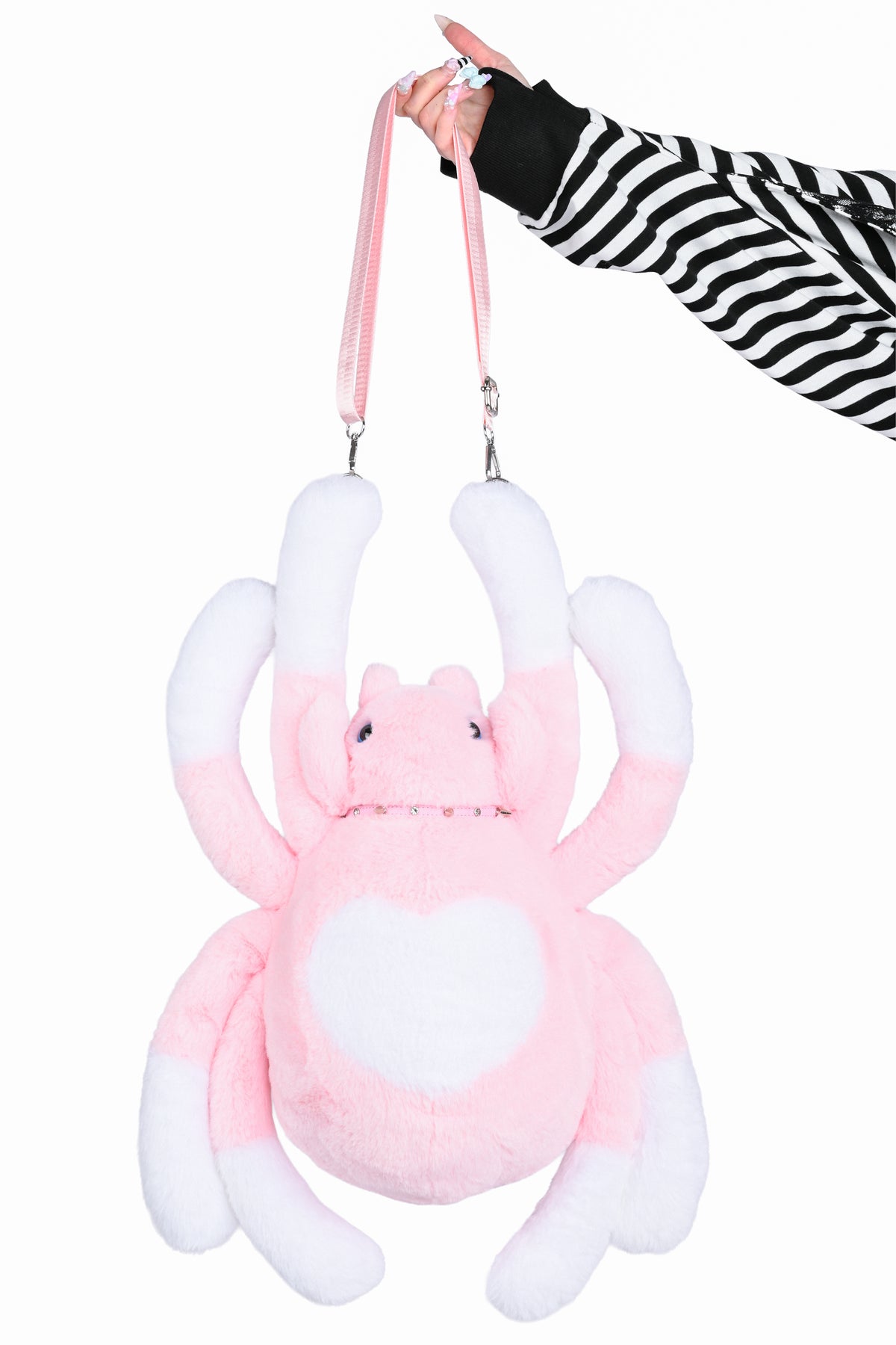 Hand holding a large pink and white spider bag by the strap.