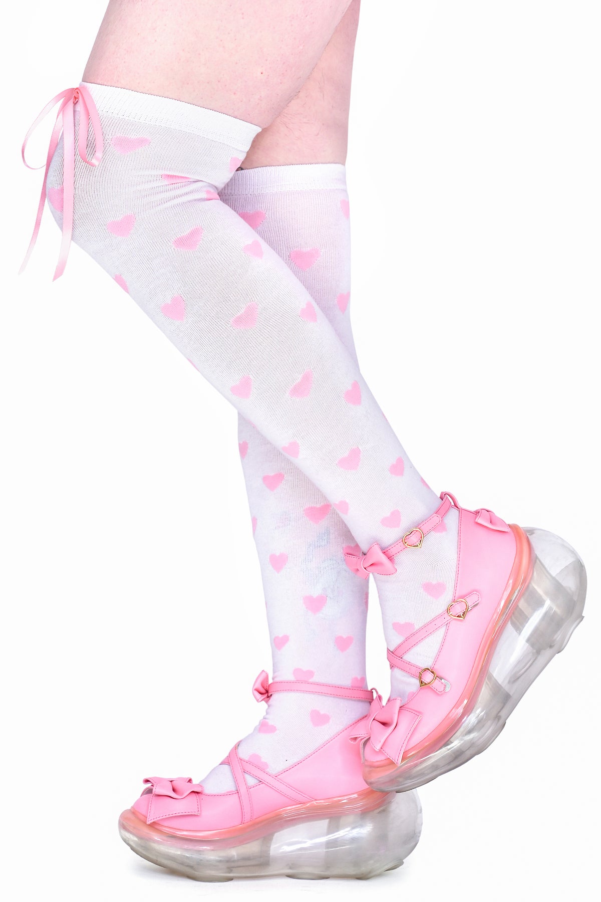 Light pink knee-high socks with pink heart patterns worn with pink platform shoes.