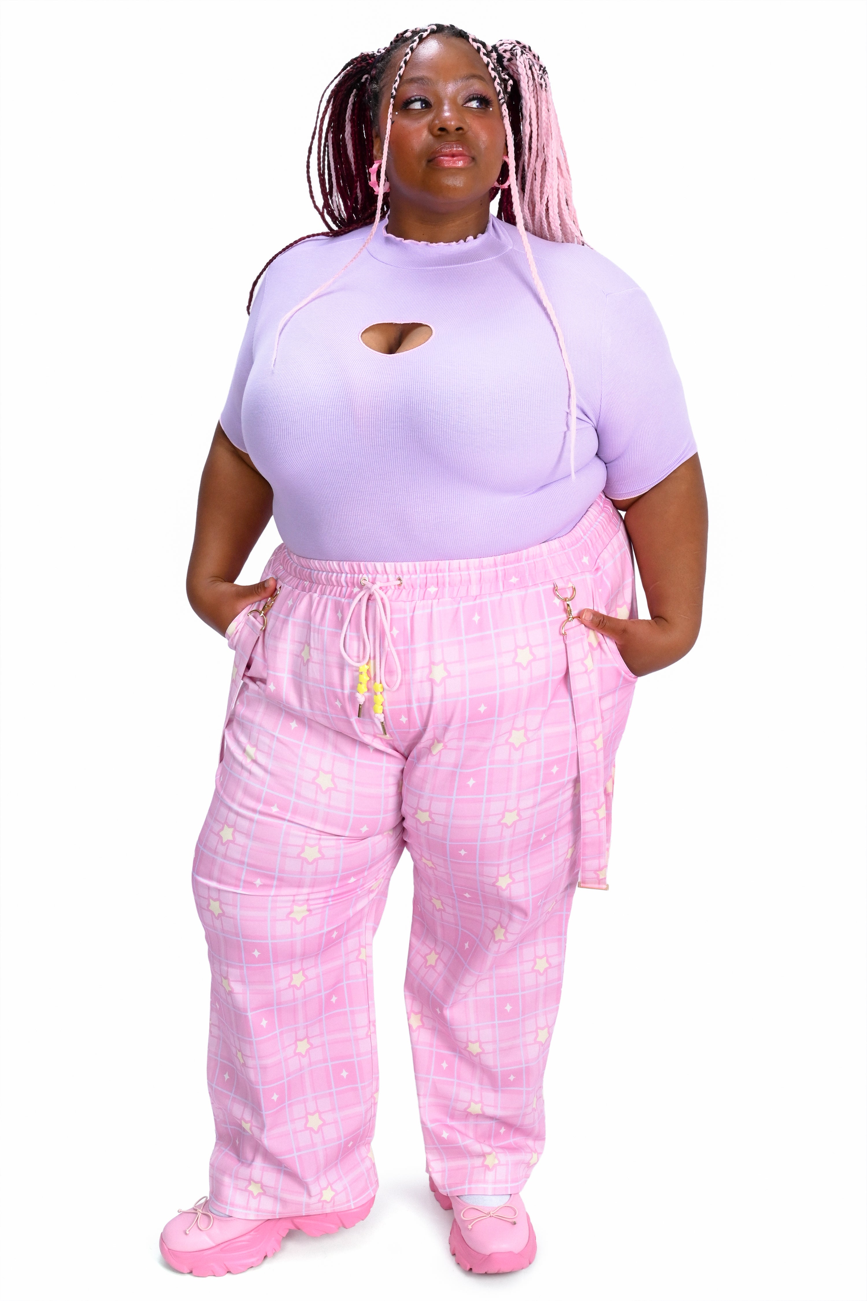 Person wearing a light purple top and pink pants with white patterns on a white background