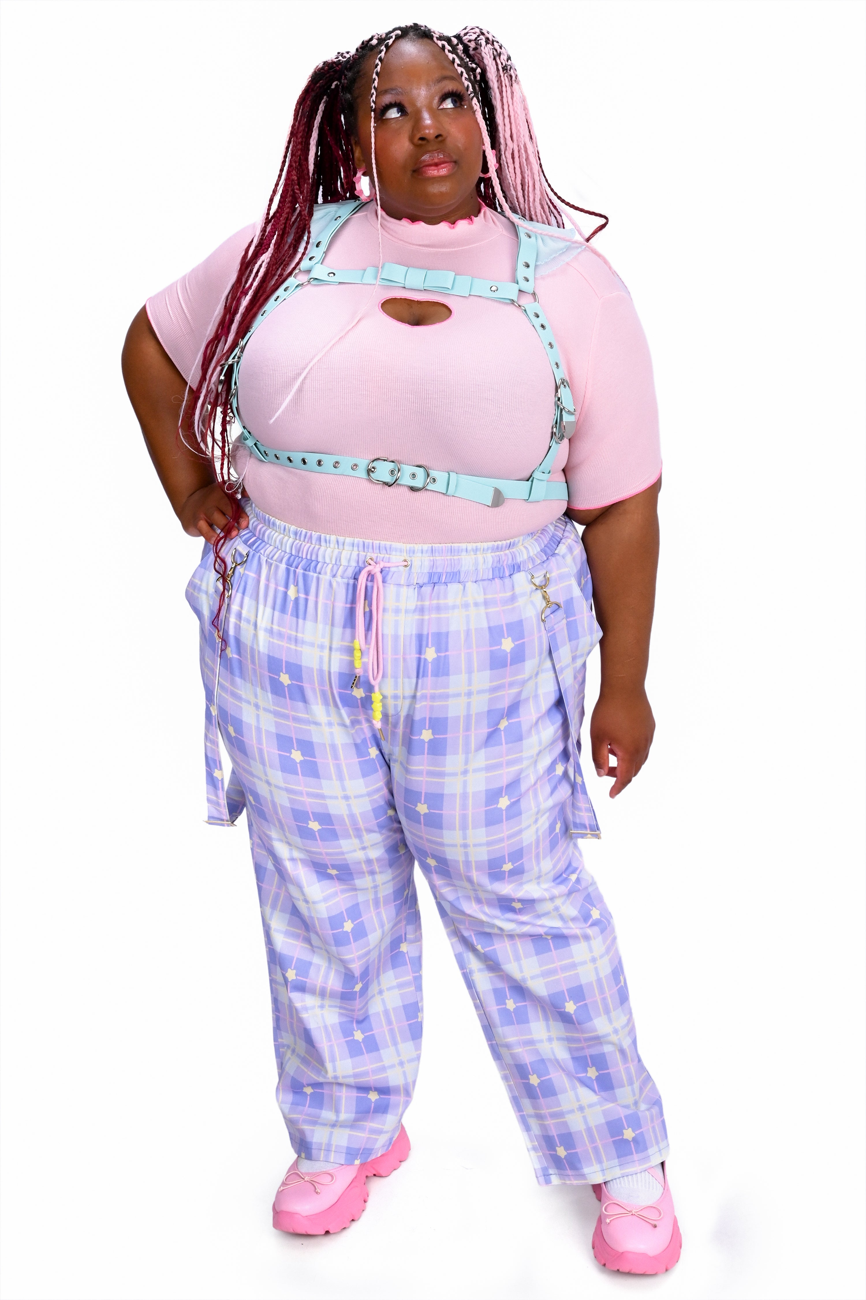 Person wearing a pink top and blue plaid pants on a white background
