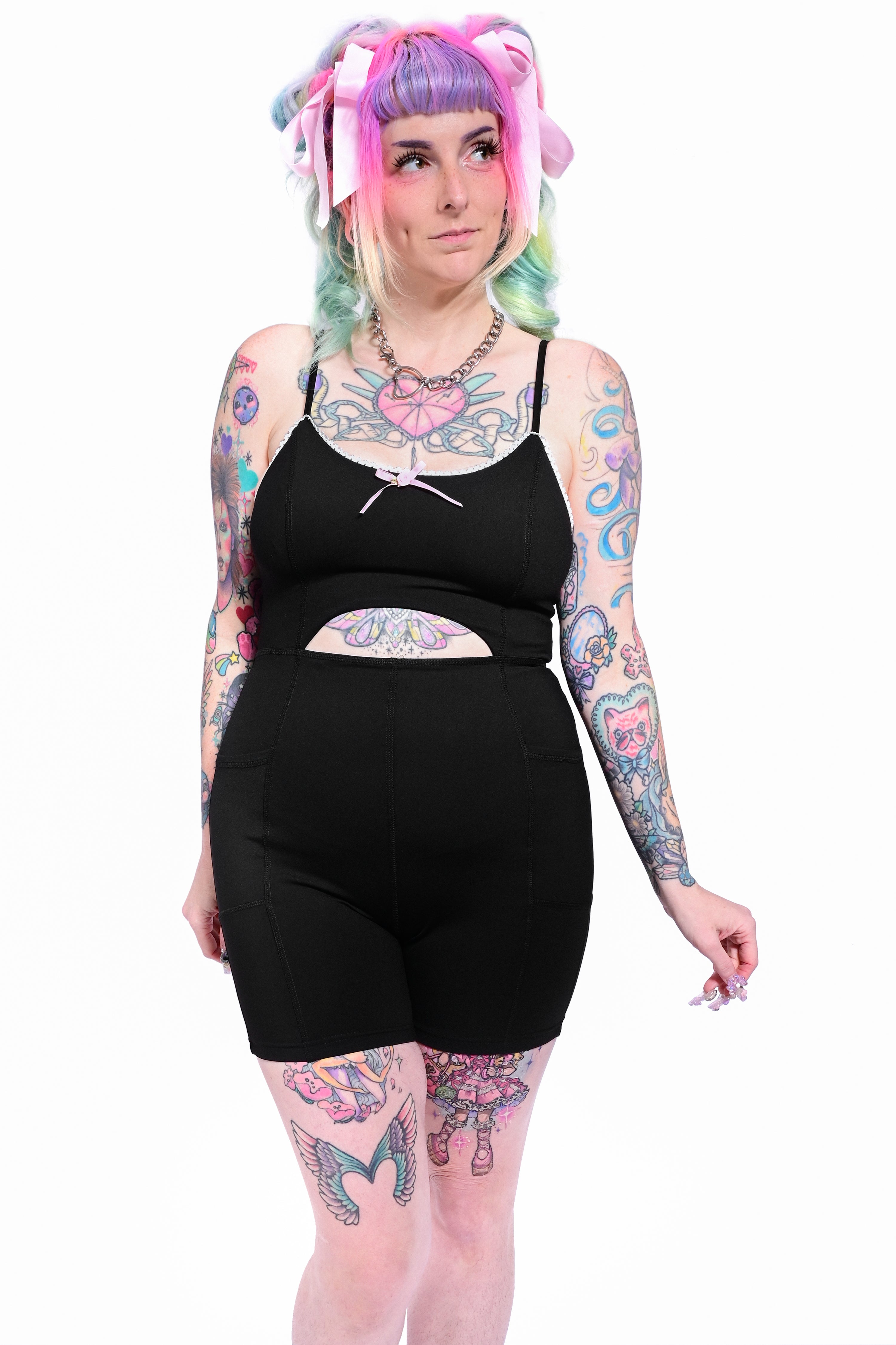 A model wearing a black bodysuit with a cutout detail at the waist and lace details along the neckline