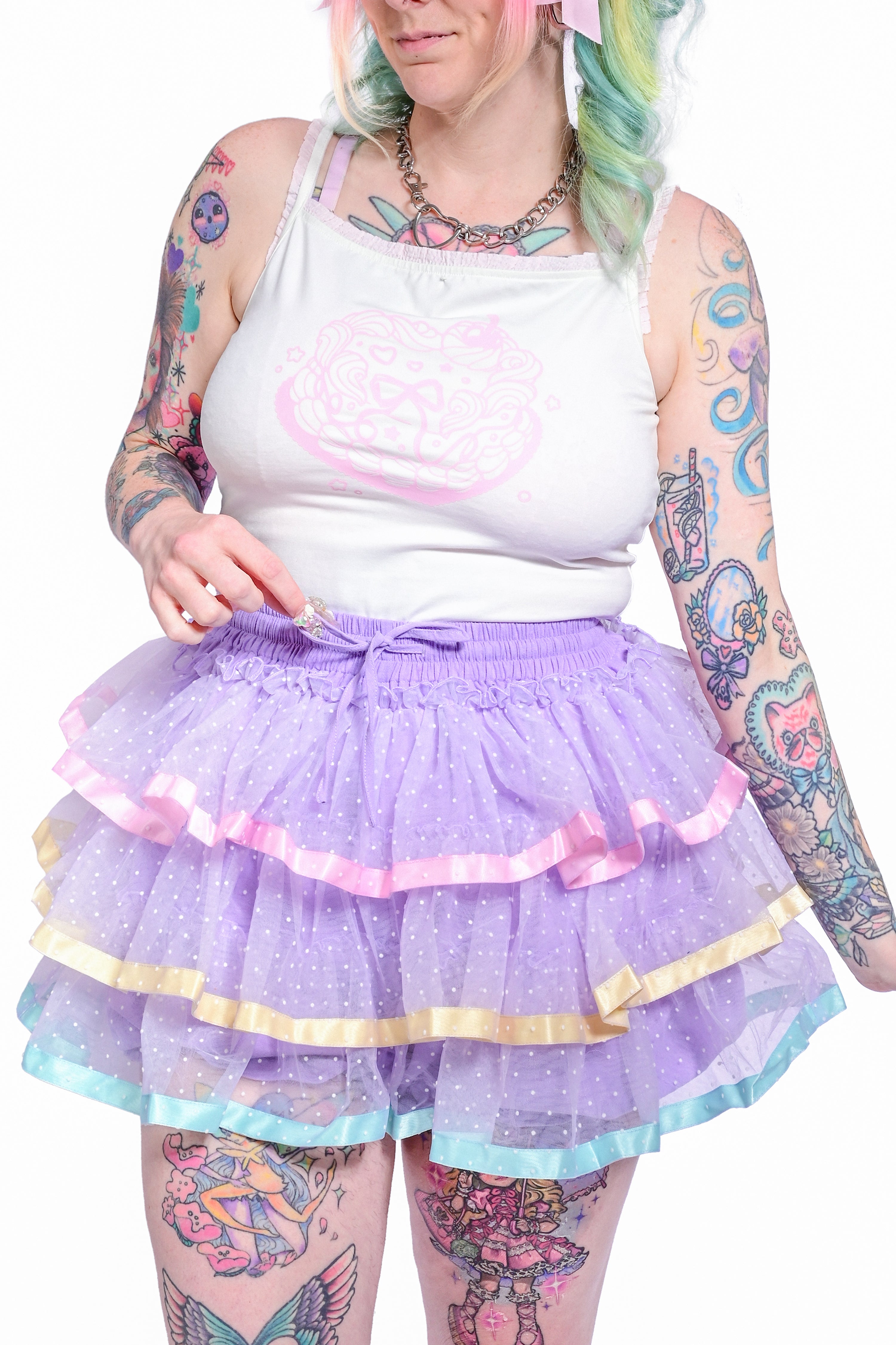 A person wearing a lavender skort with pastel ribbons and dots, paired with a white graphic camisole