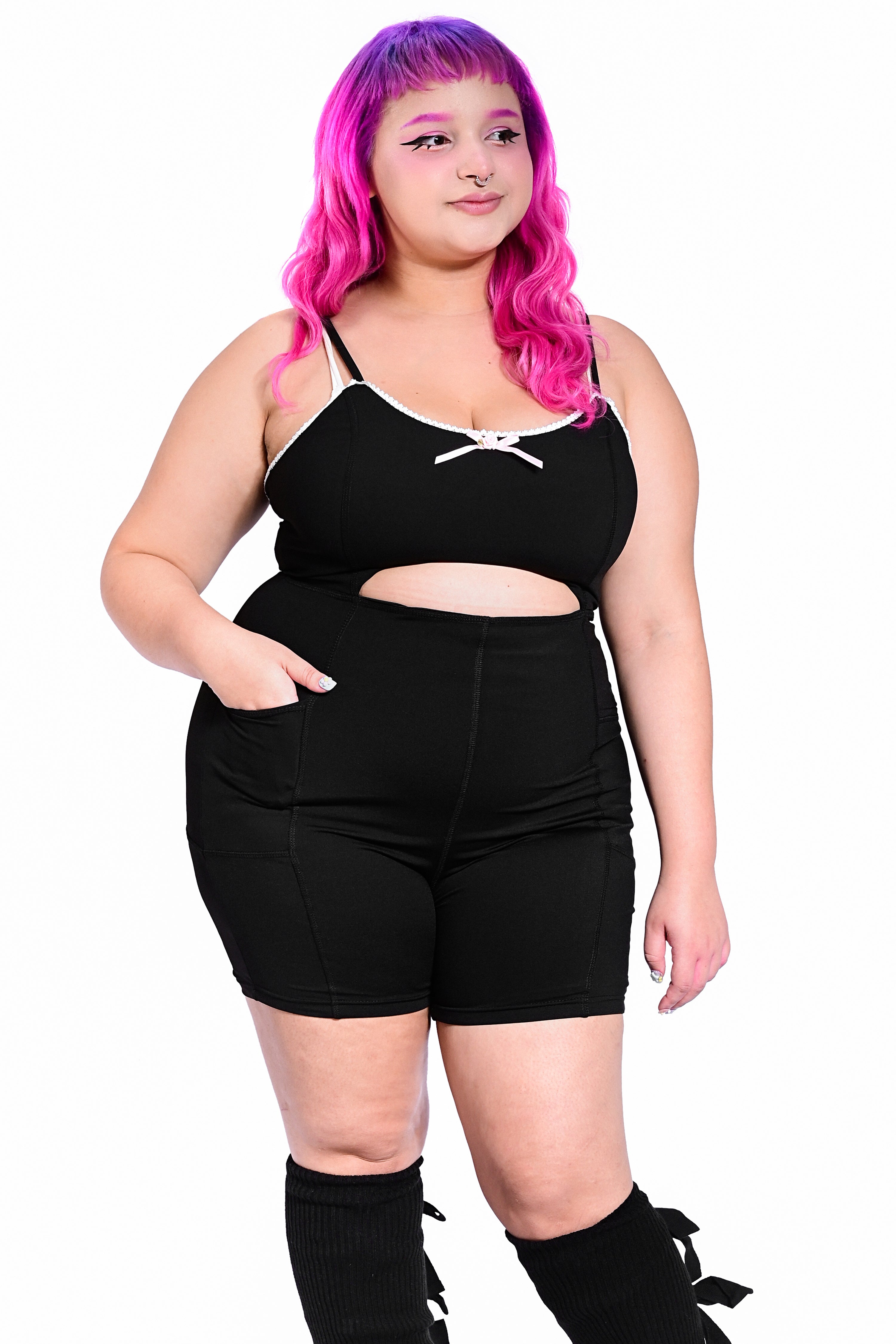 A model wearing a black bodysuit with a cutout detail at the waist and lace details along the neckline