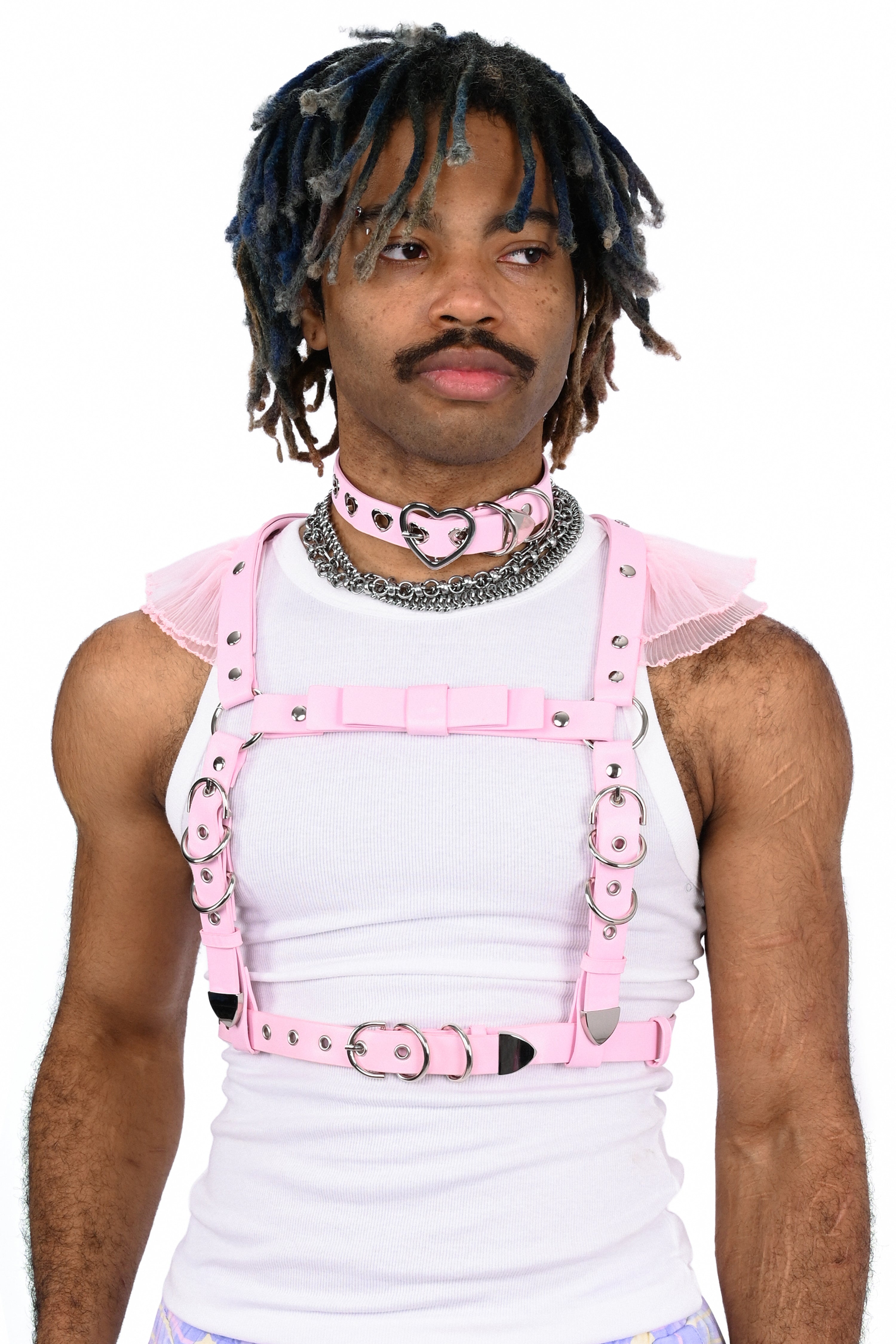 Person wearing a white tank top with pink straps and harnesses on a white background