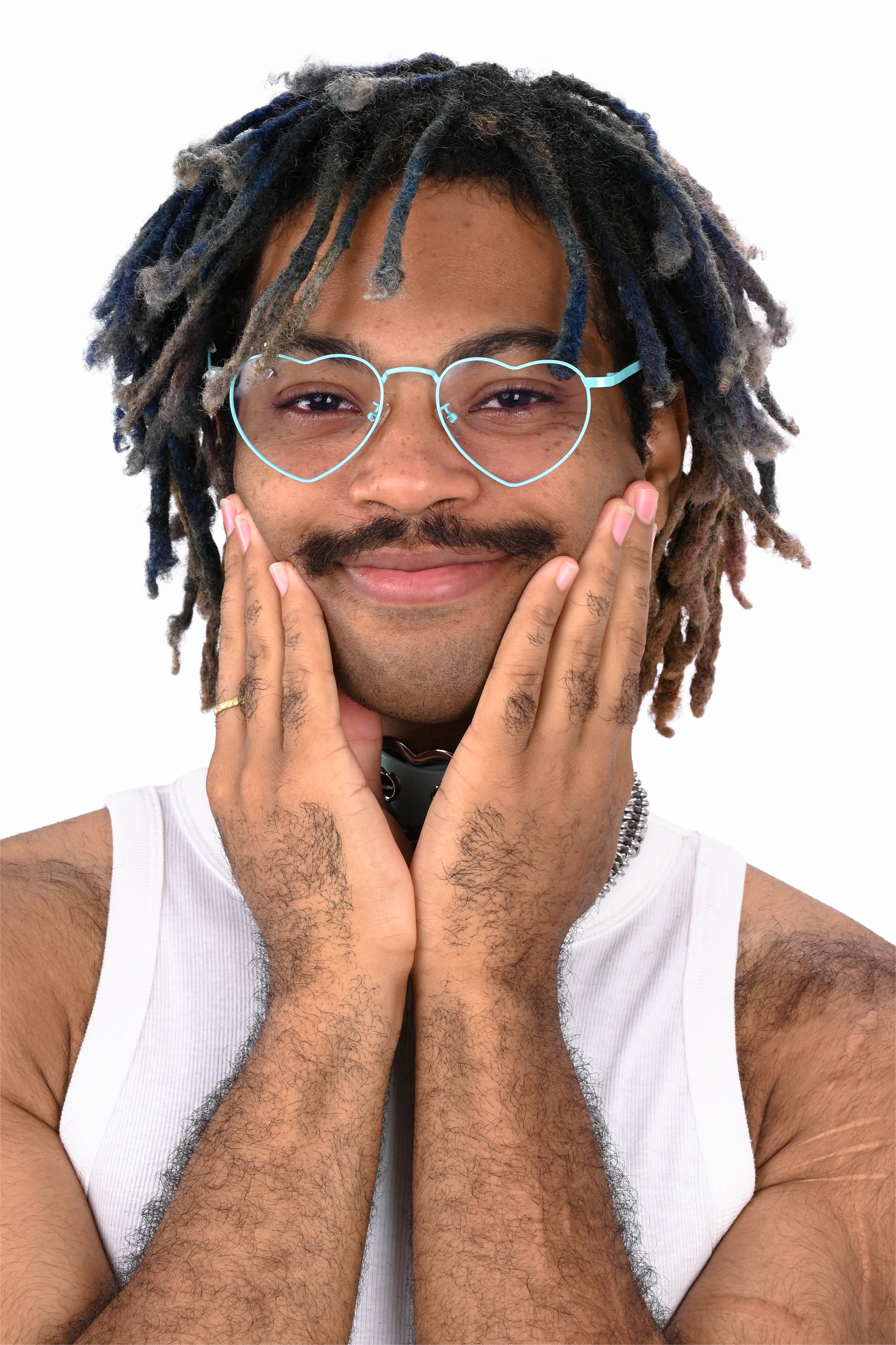 Person with dreadlocks wearing heart shaped glasses and a white tank top on a white background