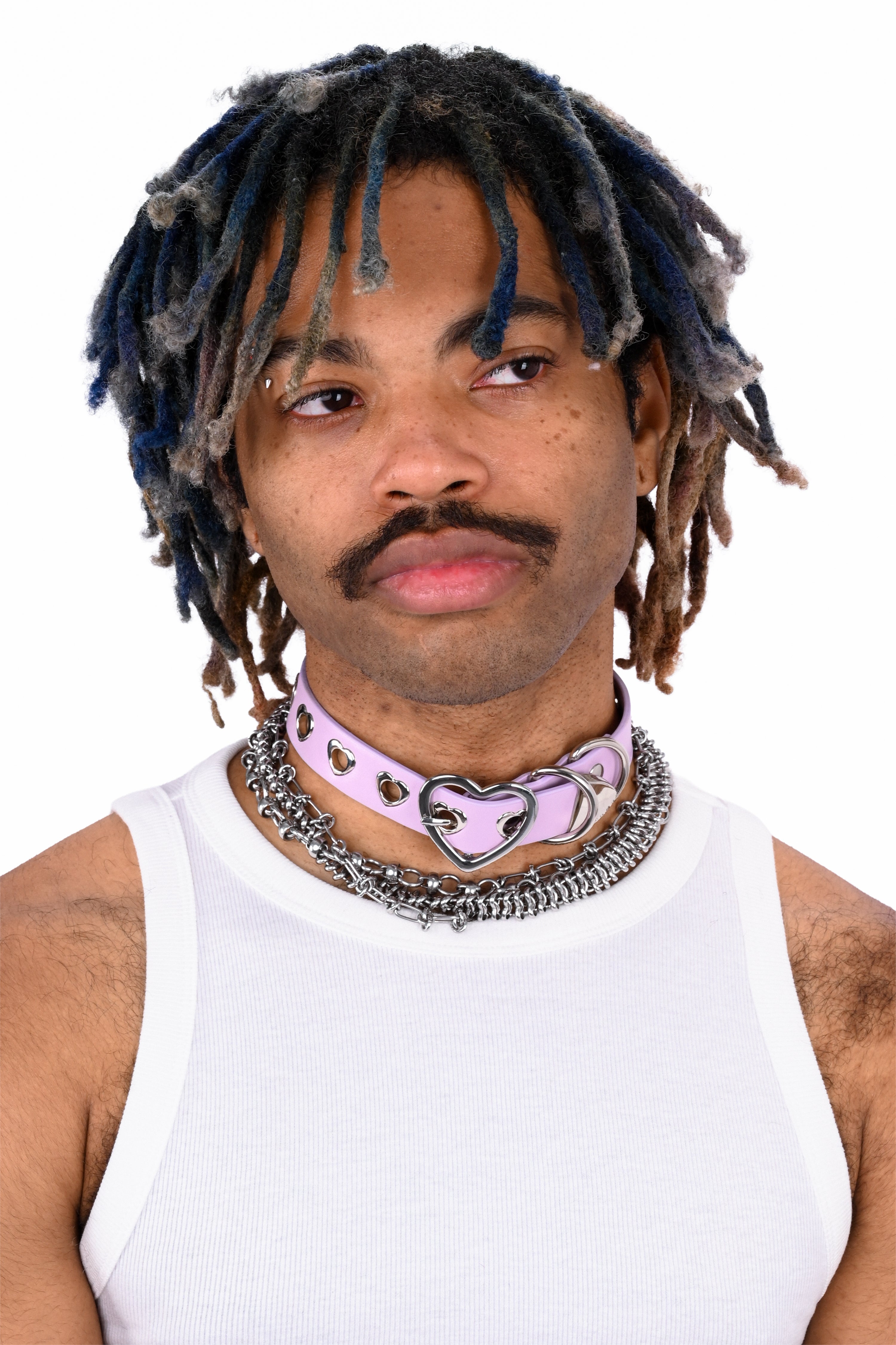 Person with dreadlocks wearing a white tank top and multiple necklaces on a white background