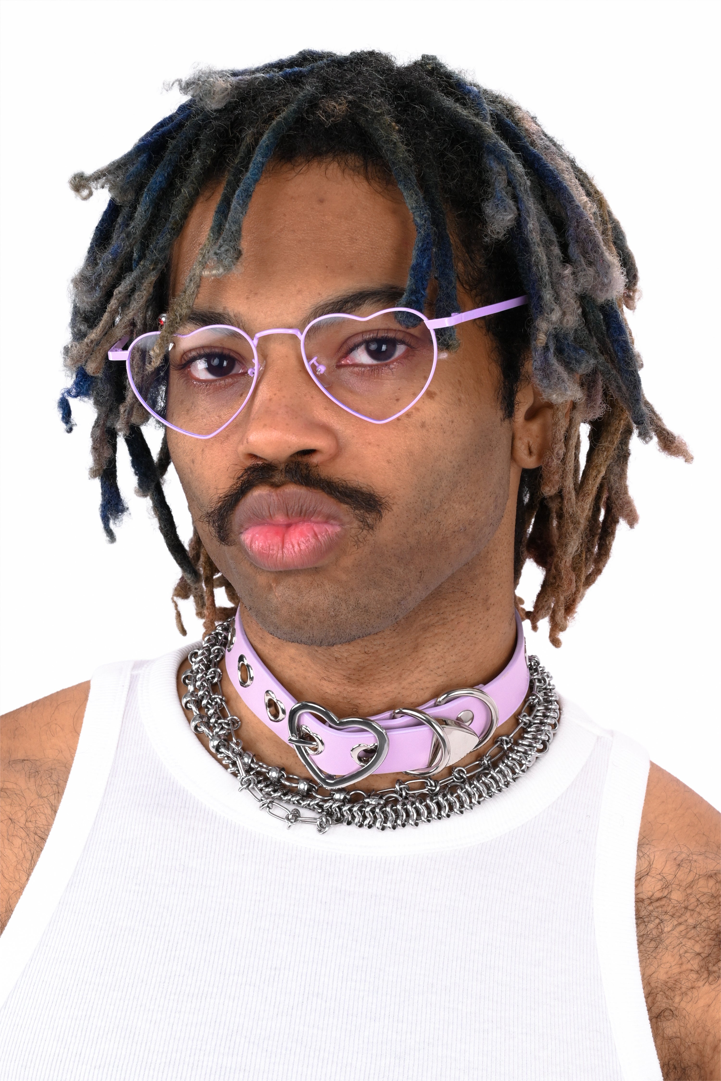 Person with dreadlocks wearing heart-shaped glasses and a white tank top on a white background