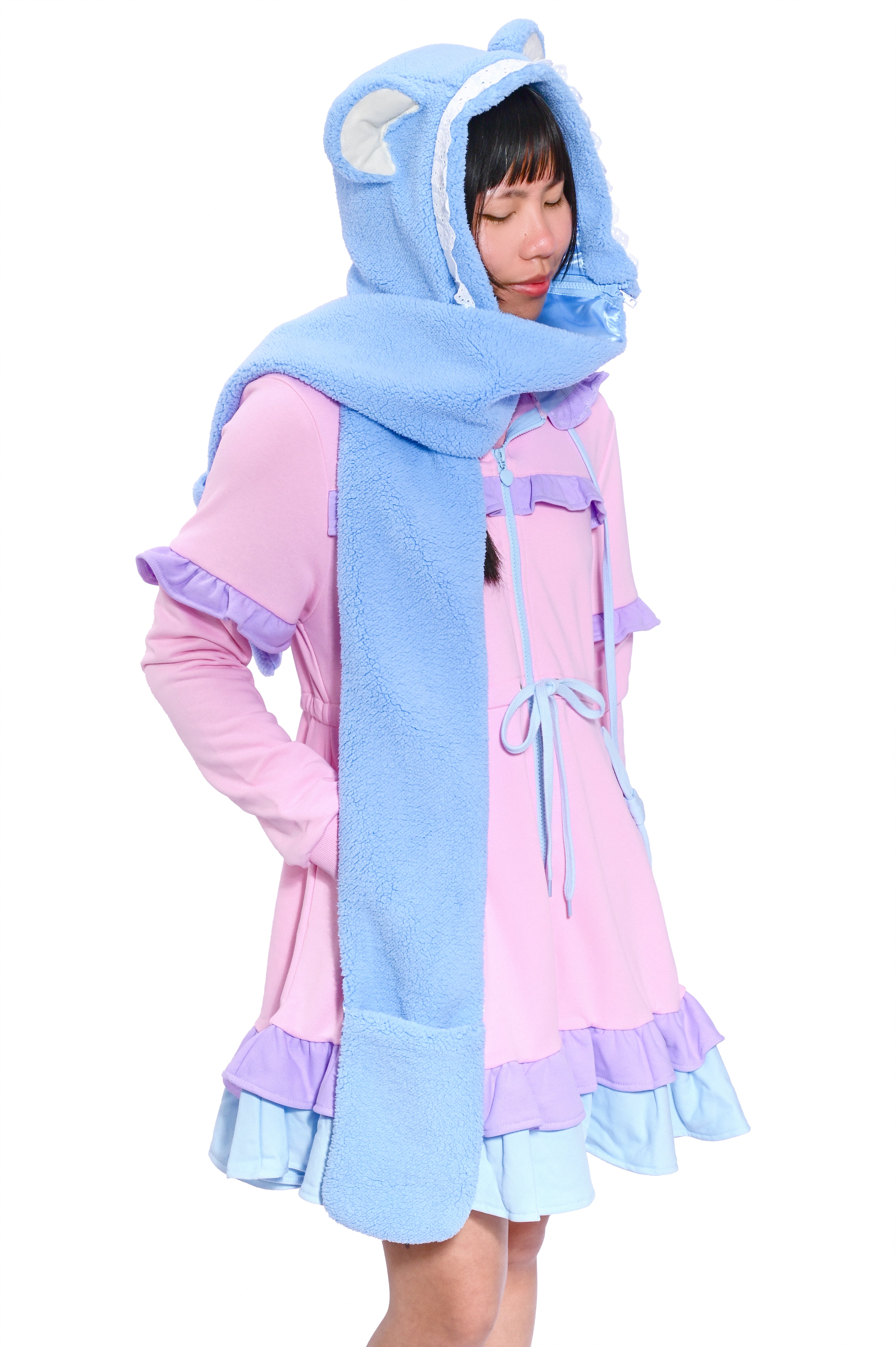 A person wearing a blue bear hooded scarf with detachable scarf extensions, paired with a pink and blue outfit.