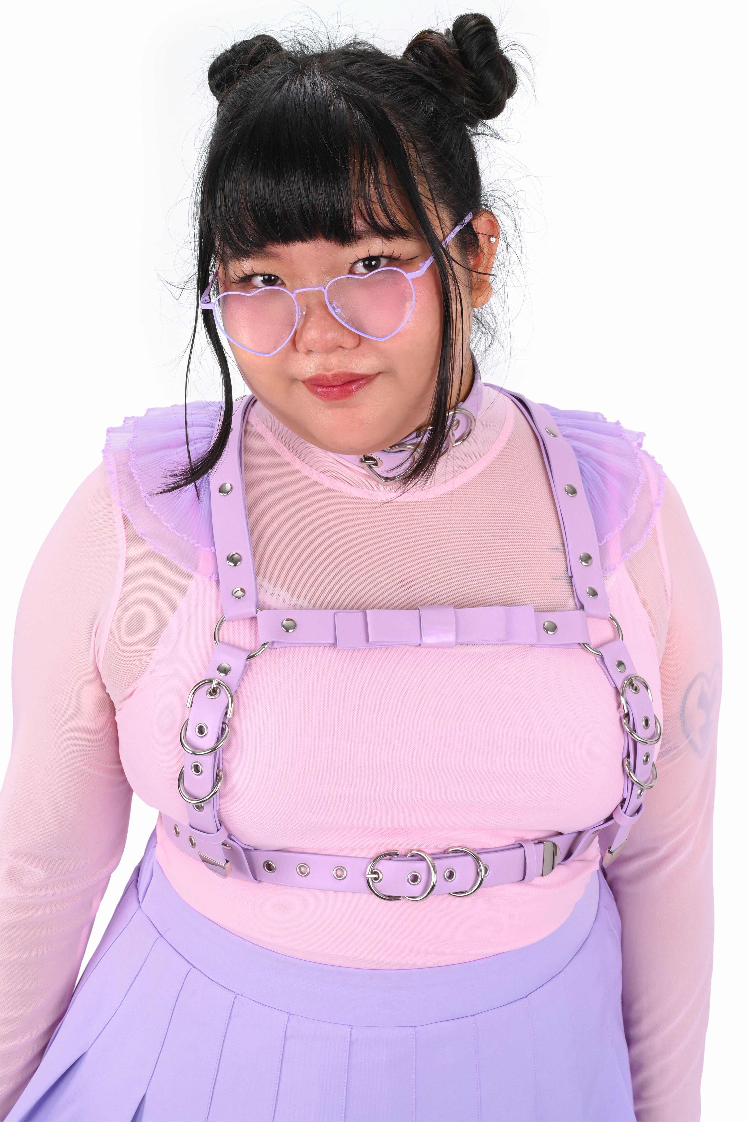 Person wearing a pink top with suspenders and a purple skirt against a white background