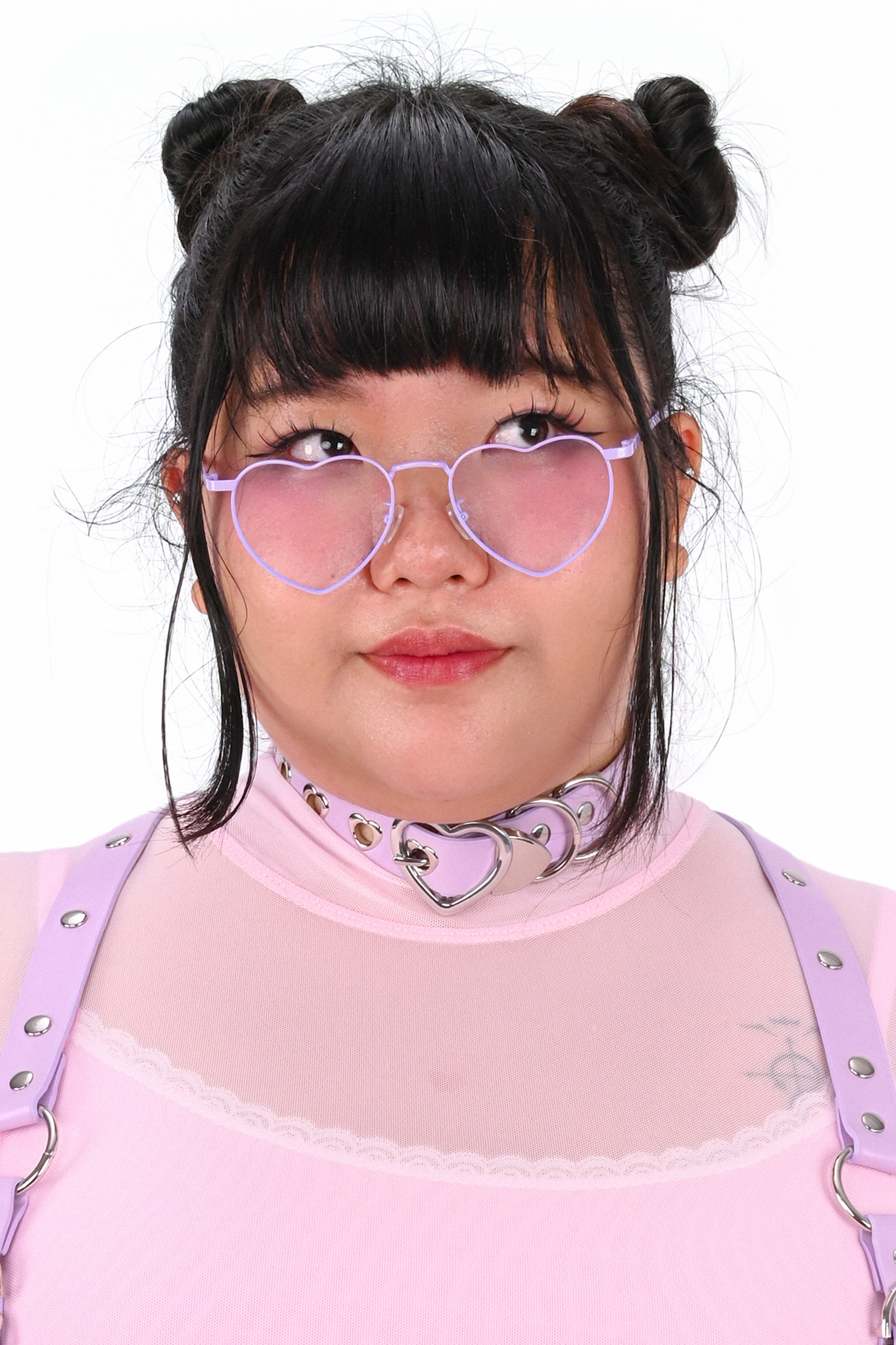 Child wearing heart-shaped sunglasses and a pink outfit with a white background