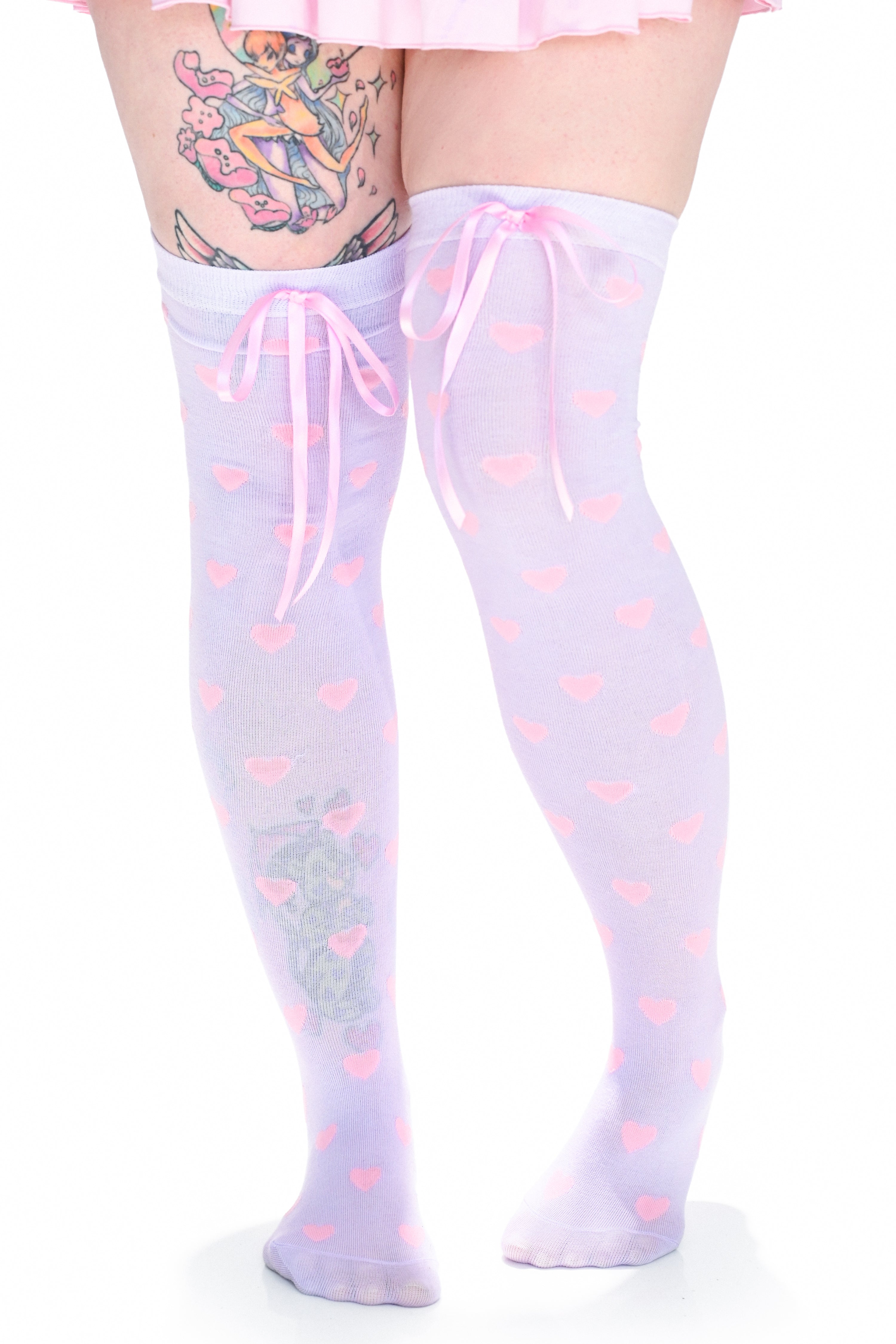 A model wearing a pair of lavender over-the-knee socks with pink hearts and a pink ribbon at the top