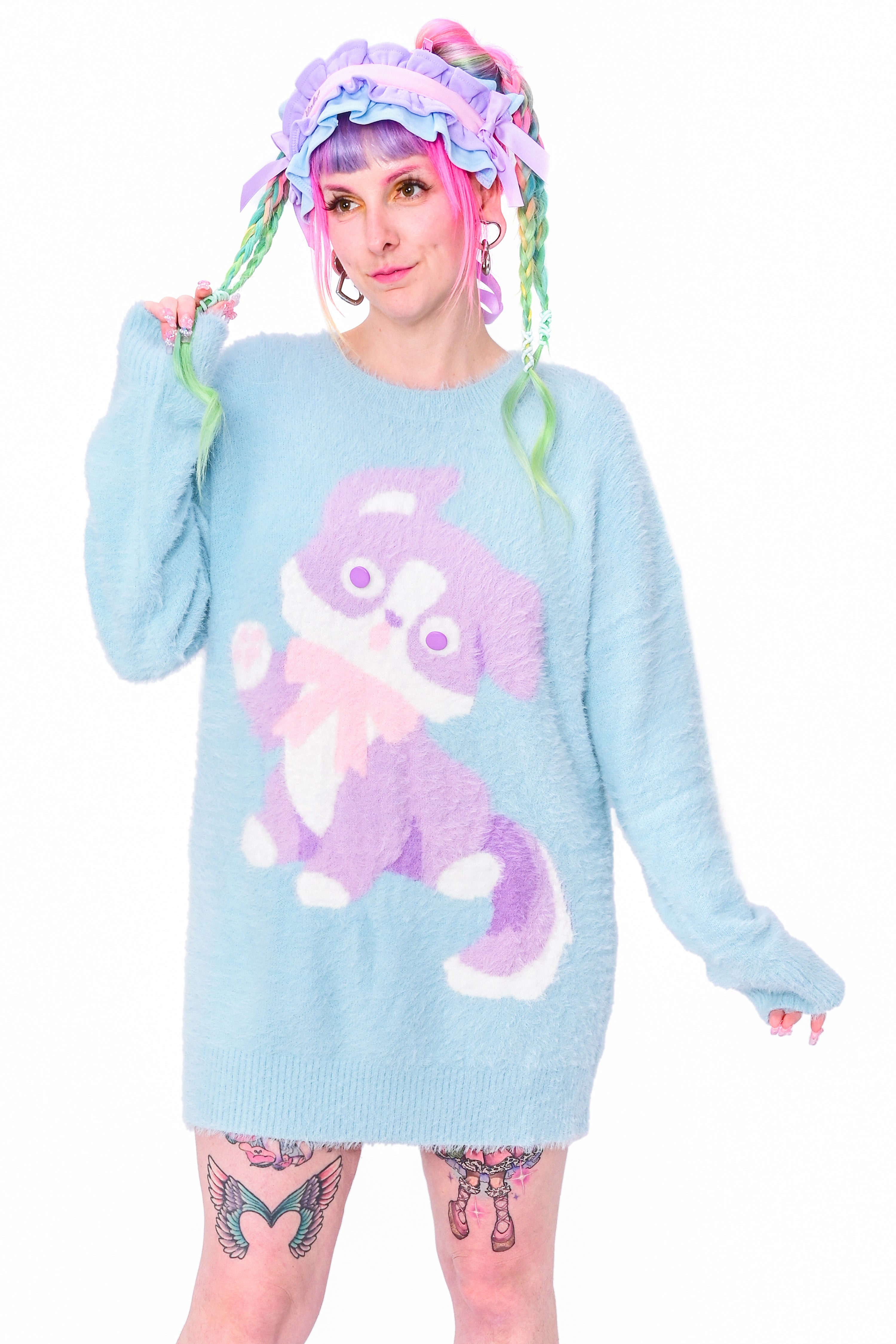 A person wearing a fluffy light blue pullover with a knit puppy design.
