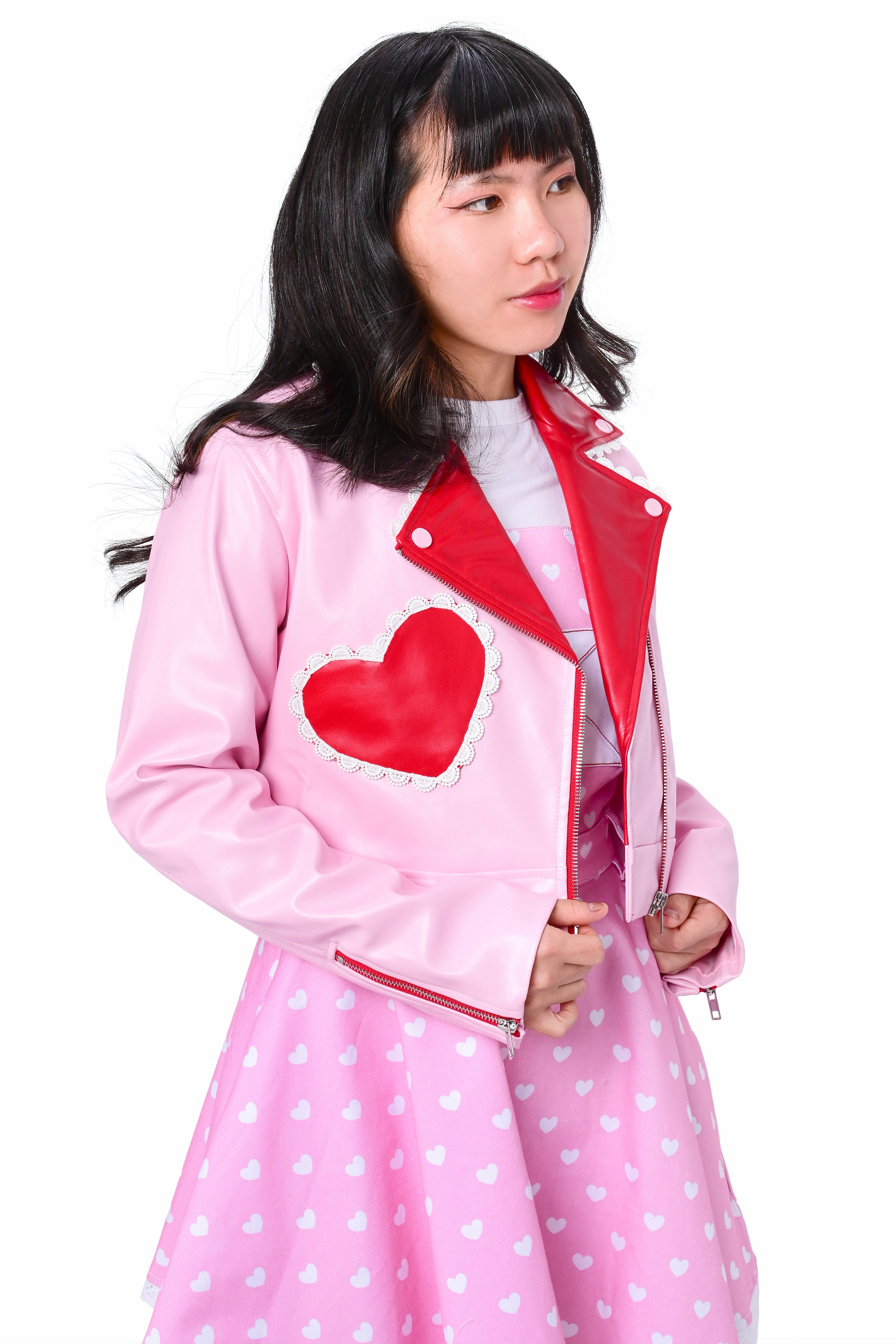 A person wearing a red and pink cropped moto jacket with heart accents, paired with a pink dress.