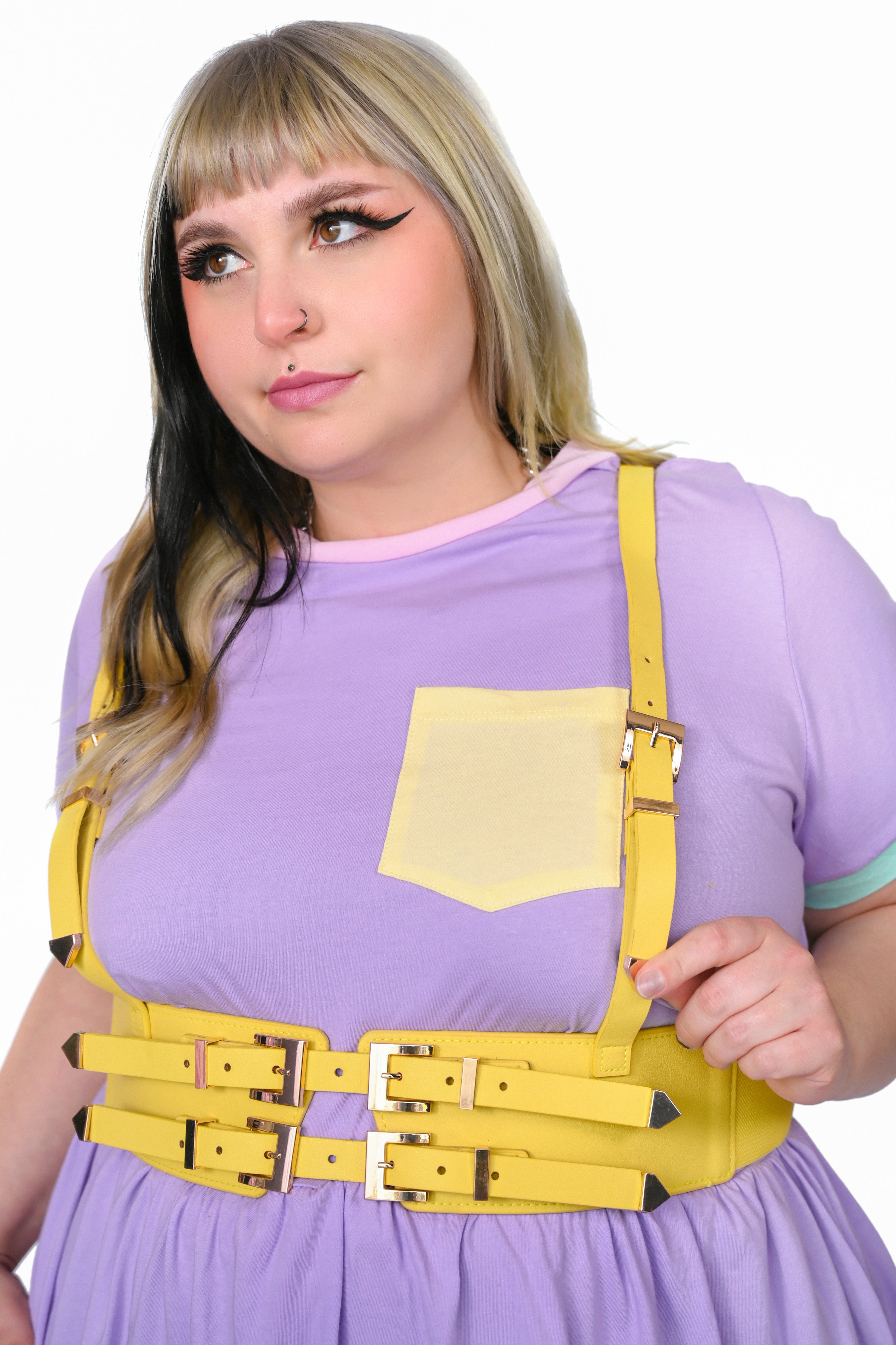 A person wearing a sunflower yellow fully adjustable vegan leather harness with gold hardware, elastic sides, and front buckles.
