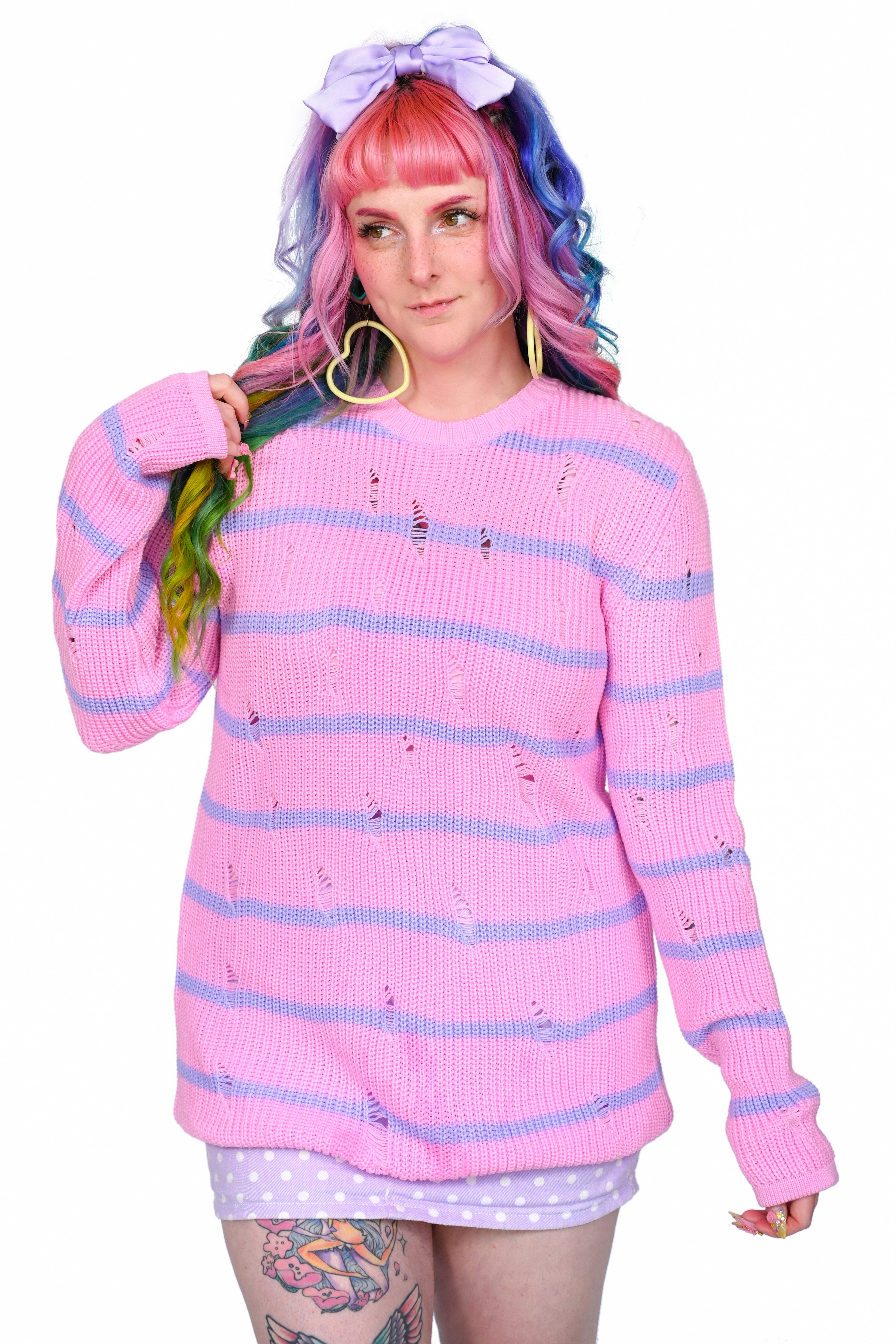 A person wearing a shredded pink sweater with lavender stripes.