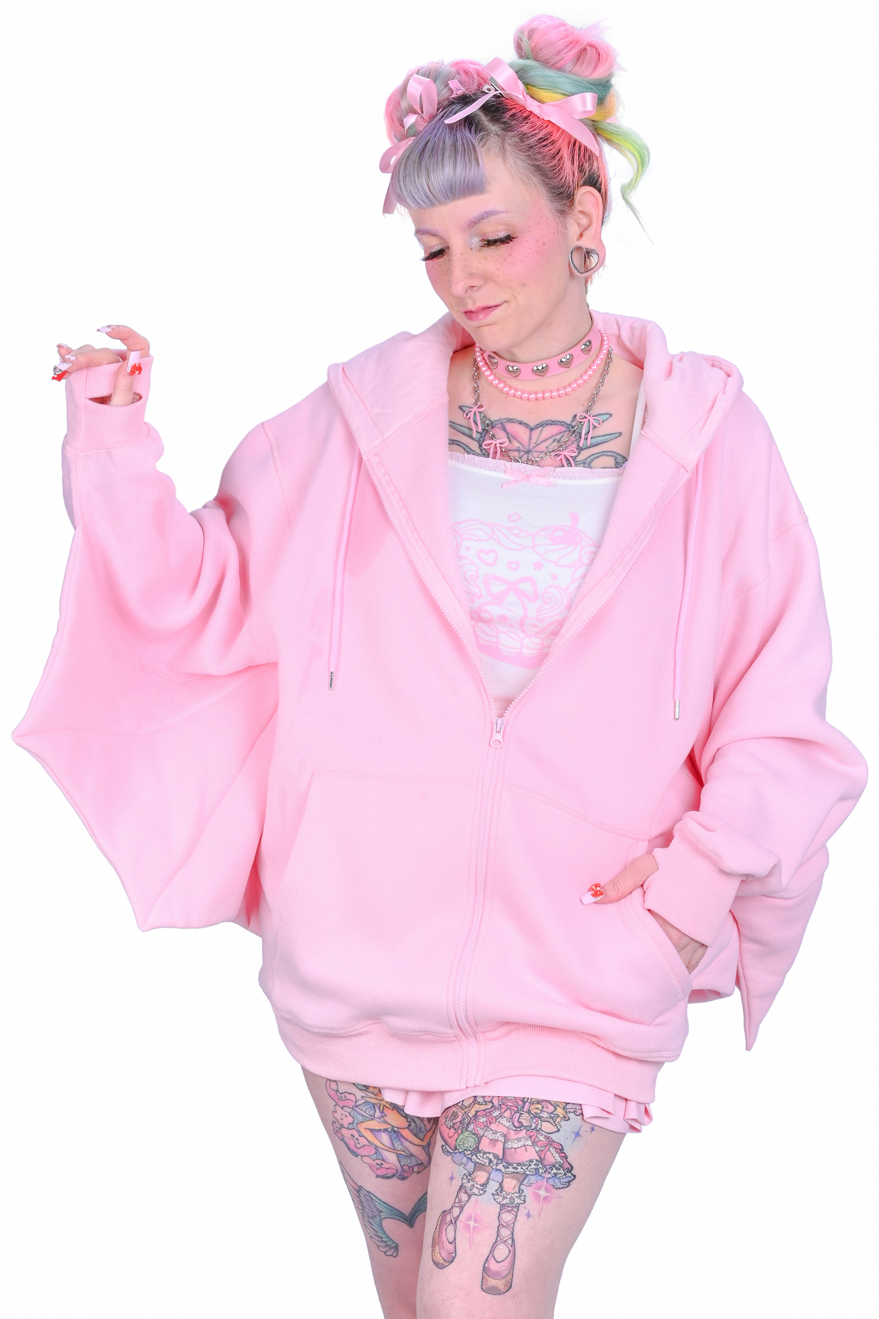 A person wearing a oversized pink hoodie with bat ears and wing-like sleeves