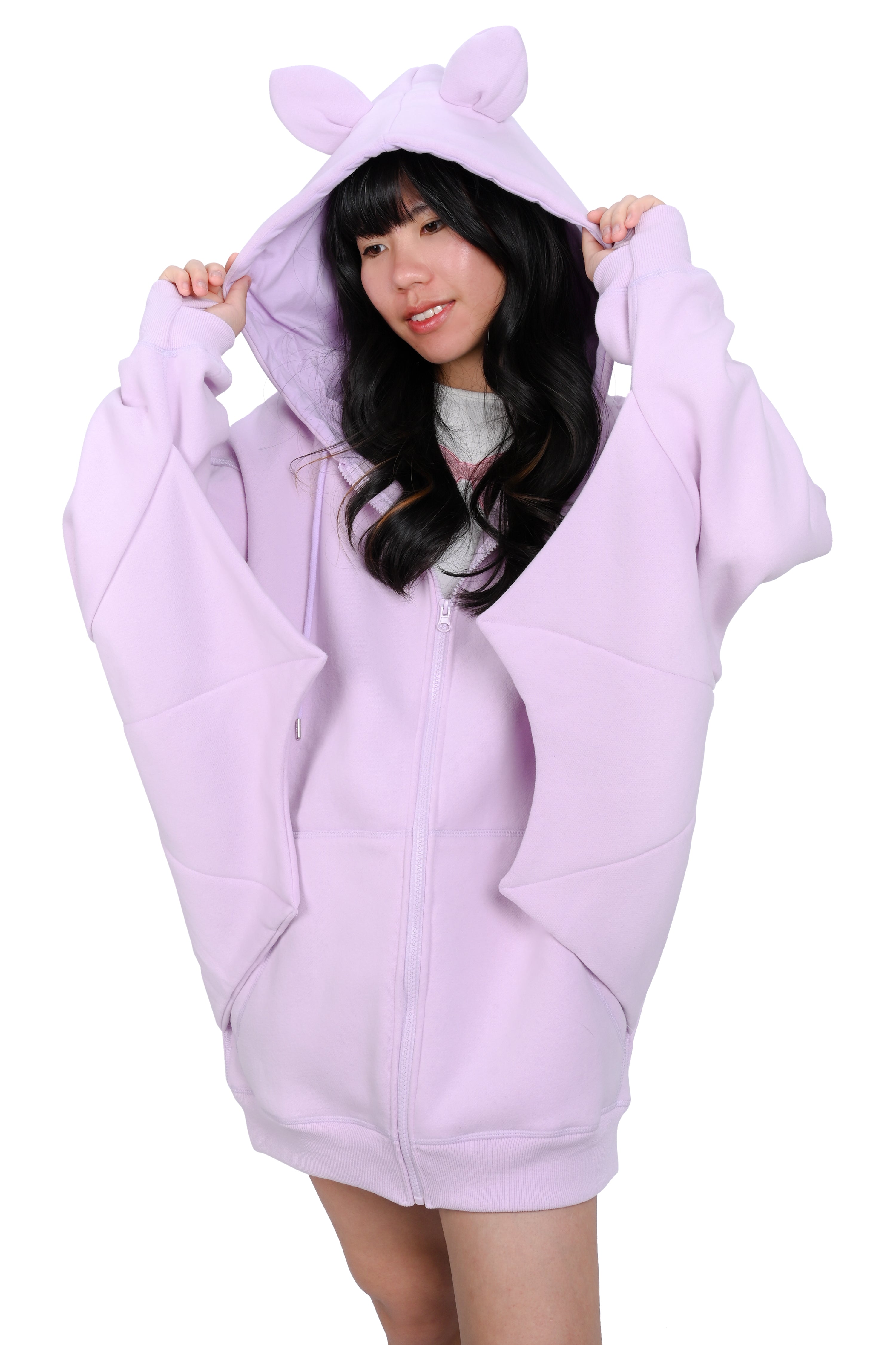 A person wearing a oversized lavender hoodie with bat ears and wing-like sleeves