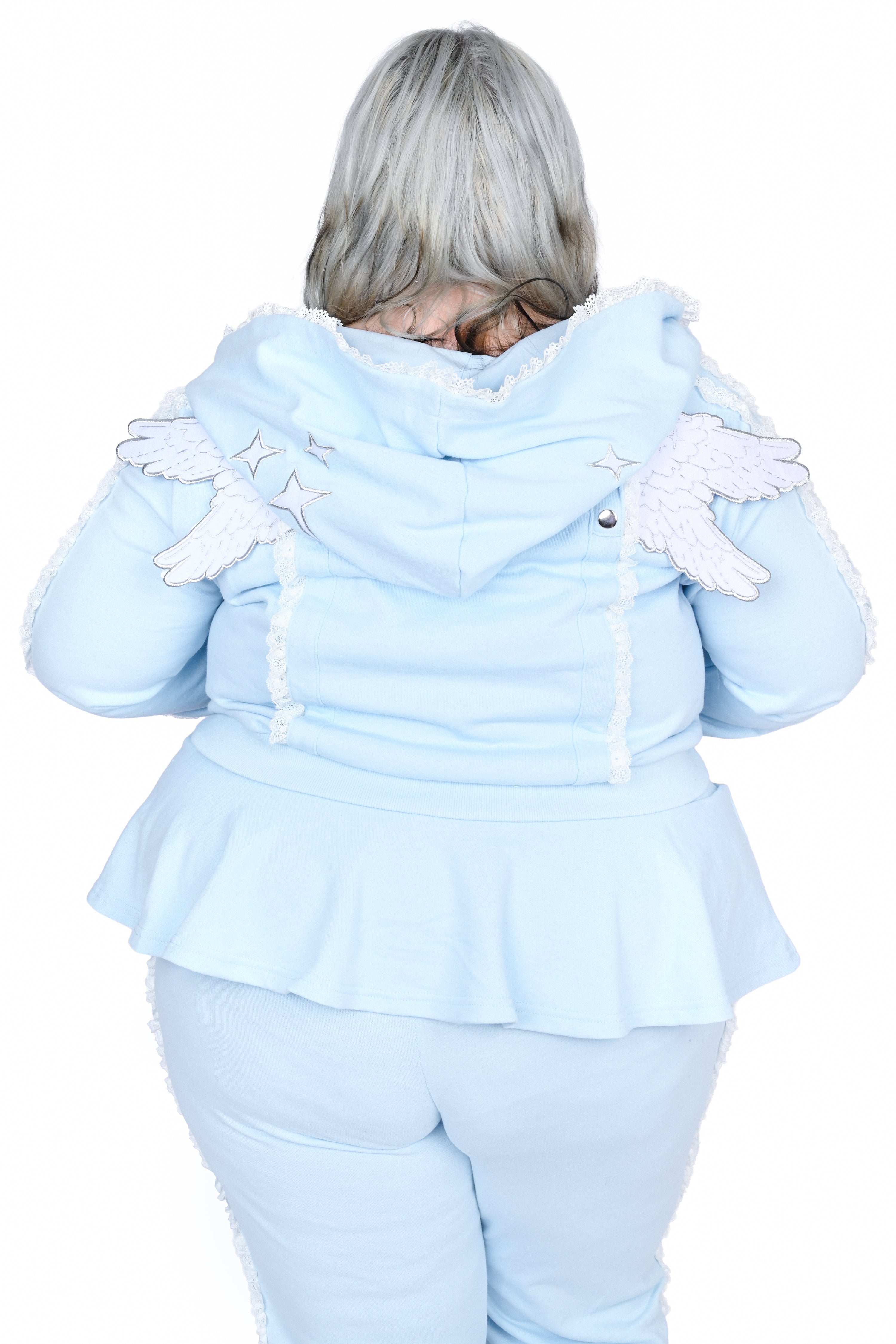 A person shown from the back wearing a light blue hooded outfit with white angel wings and white fringe trim, photographed against a plain white background.