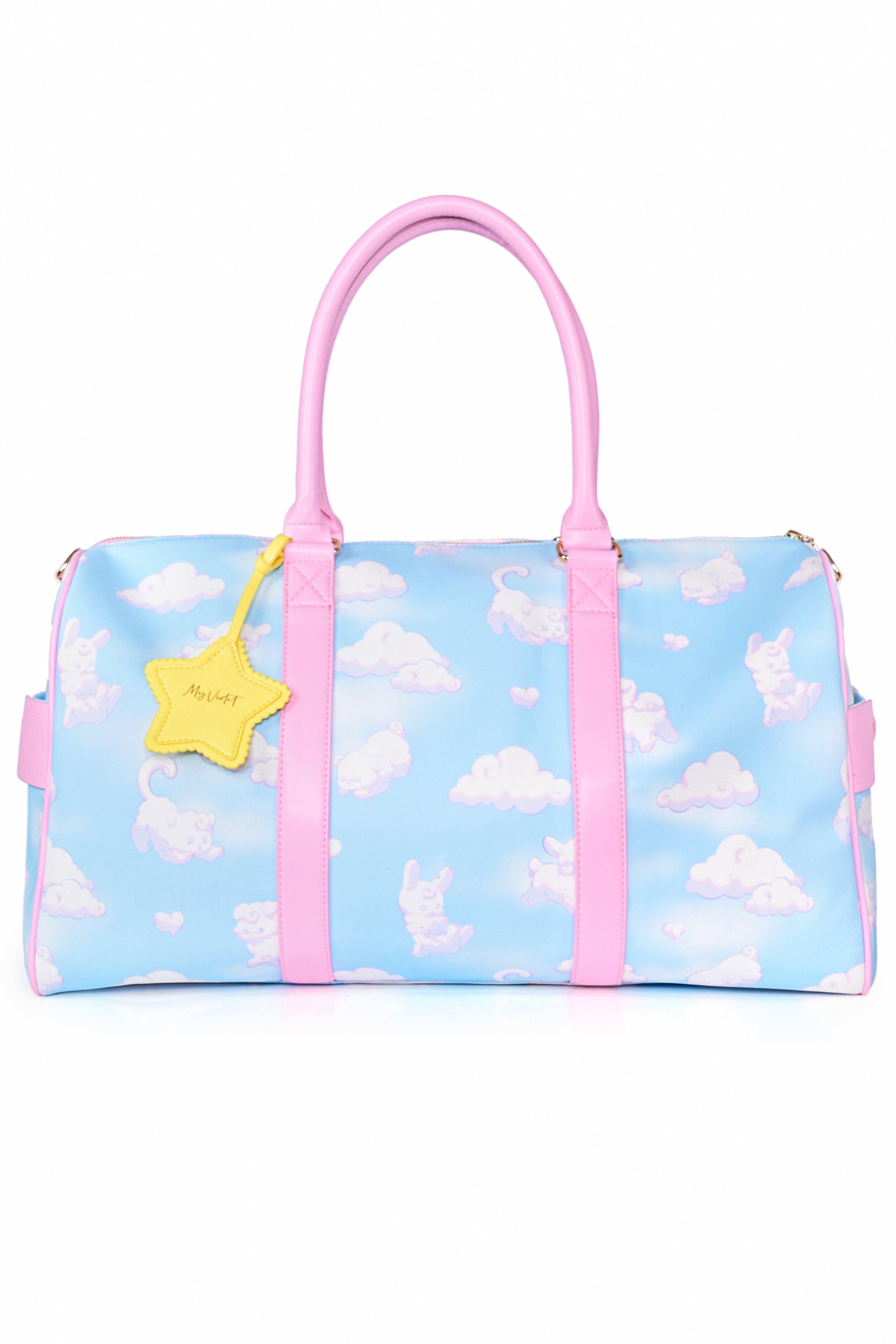 A weekender bag with a blue and white cloud pattern, featuring pink trim, two handles, and a detachable shoulder strap. It includes a yellow star-shaped charm attached to one of the handles.