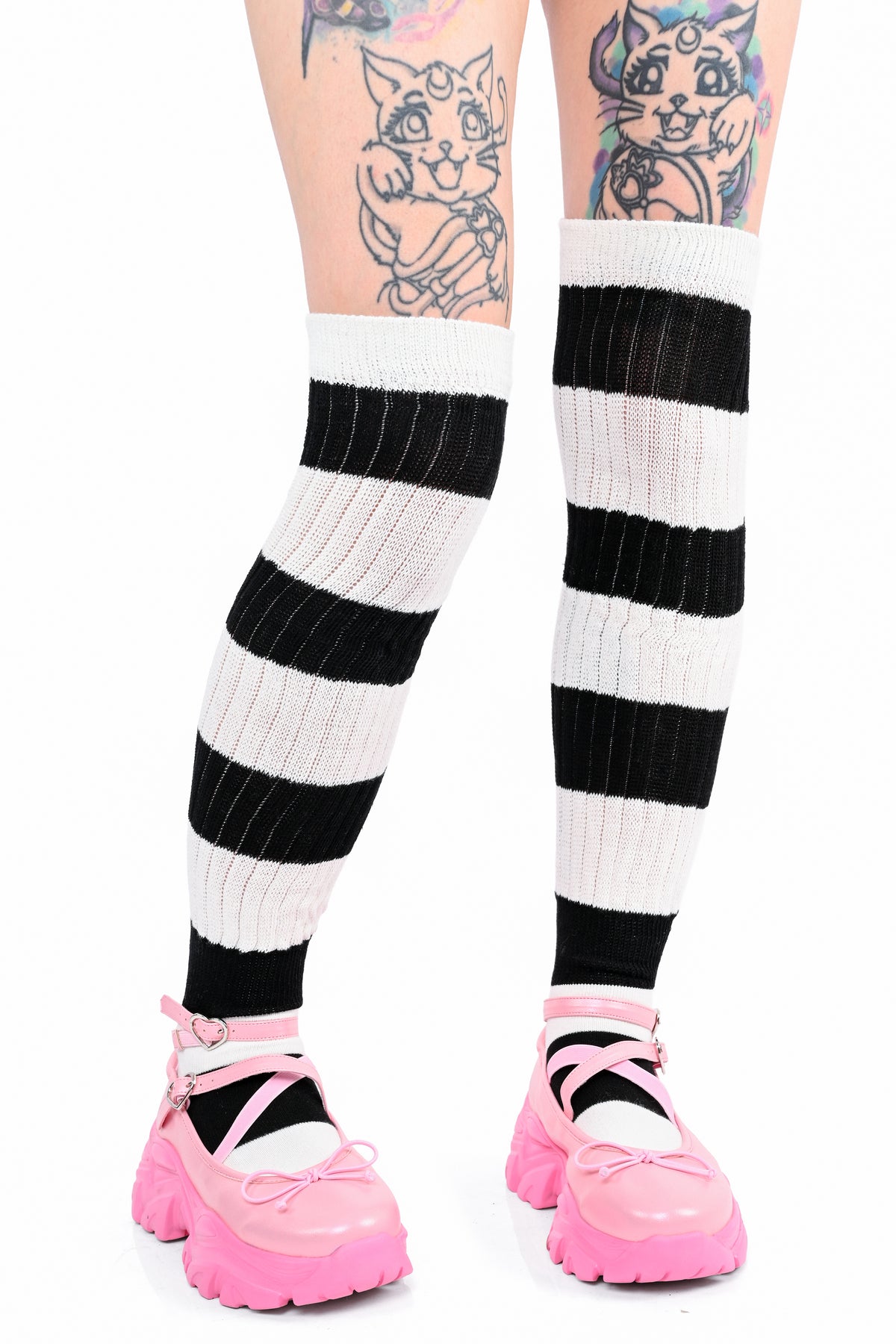 Black and white striped ribbed knee-high socks worn by a model with pink Mary Jane shoes, shown from the thighs down against a white background.