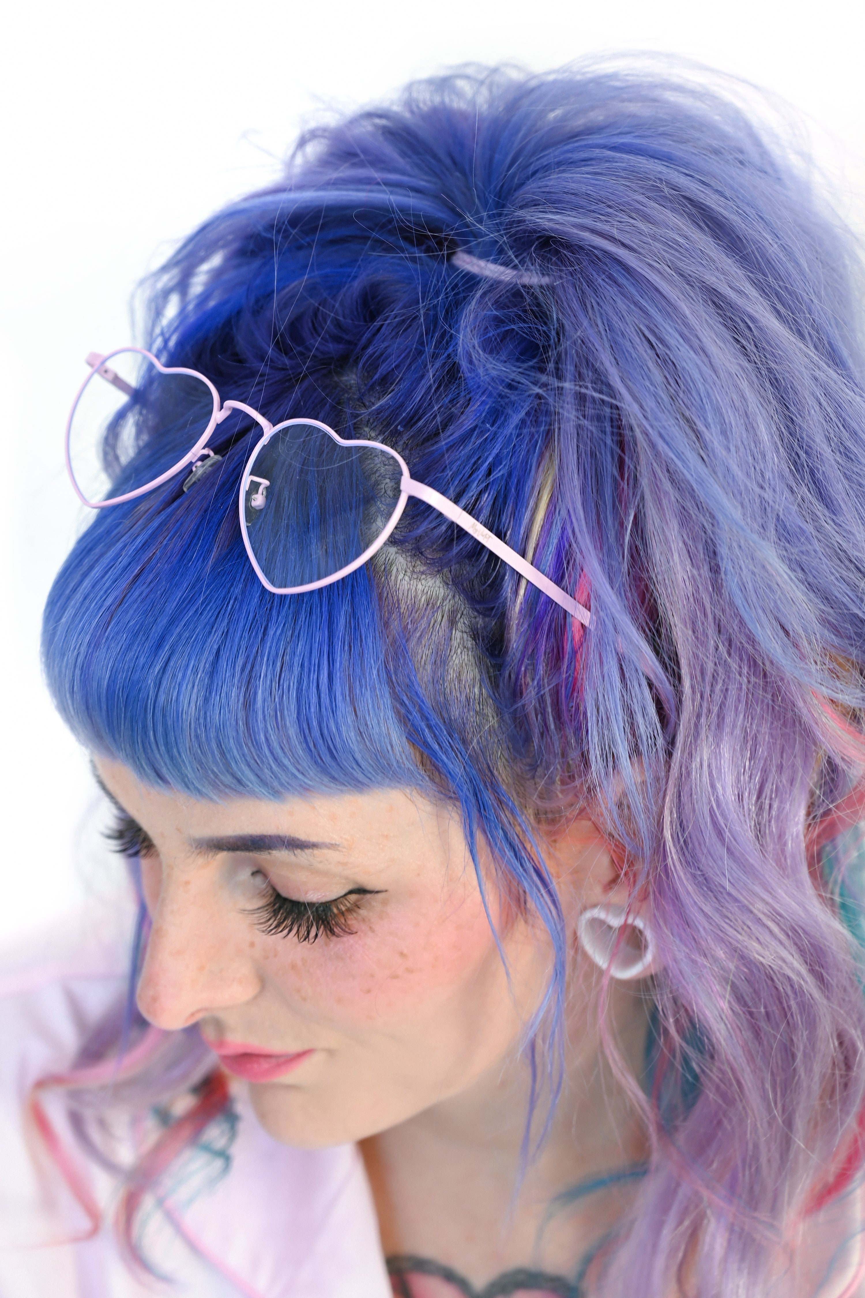 A person wearing pink heart-shaped glasses on a white background