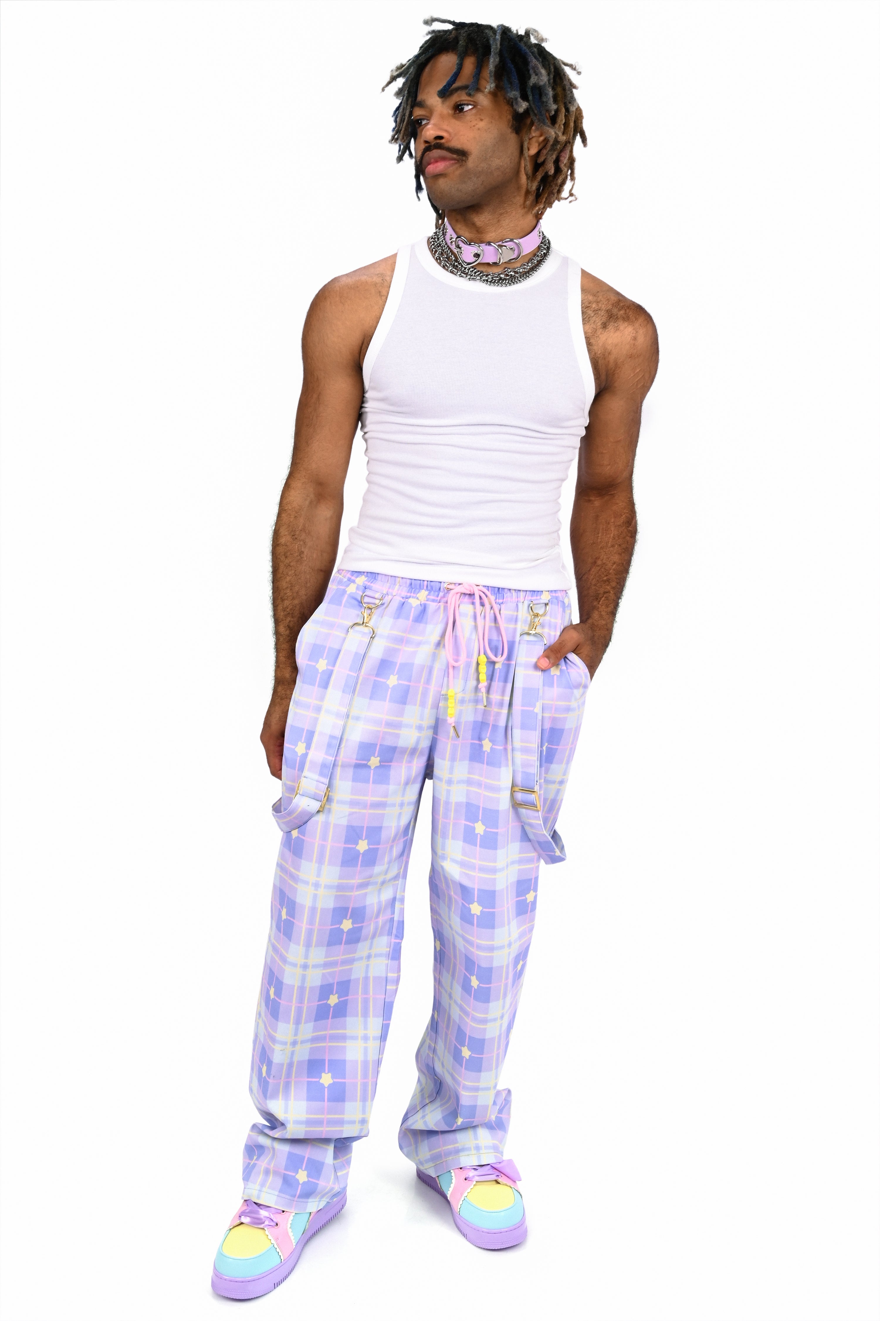 Person wearing a white tank top and colorful plaid pants on a white background