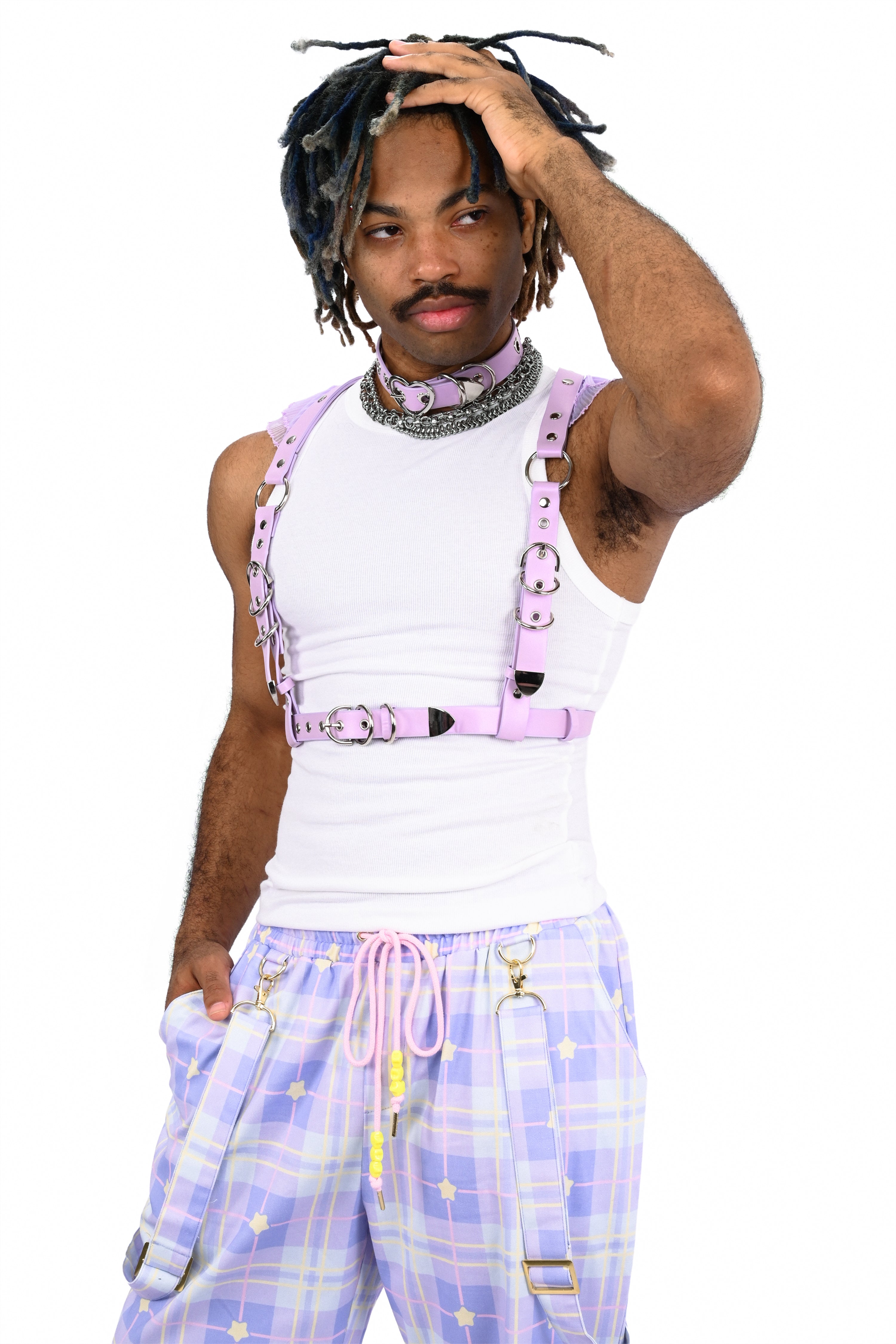 Person wearing a white tank top with pink suspenders and plaid pants on a white background