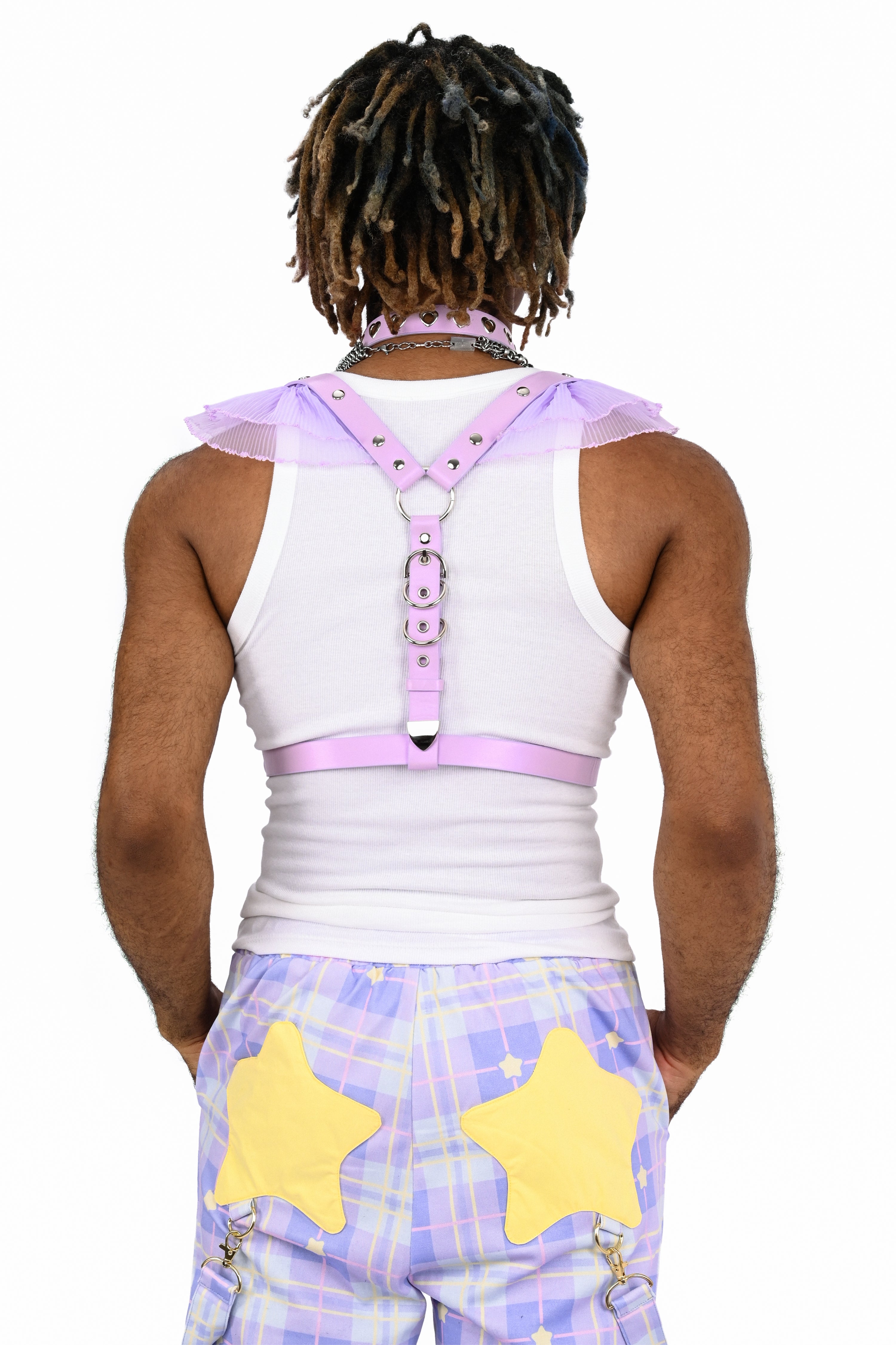Person wearing a white tank top with a pink harness and star-patterned pants on a white background